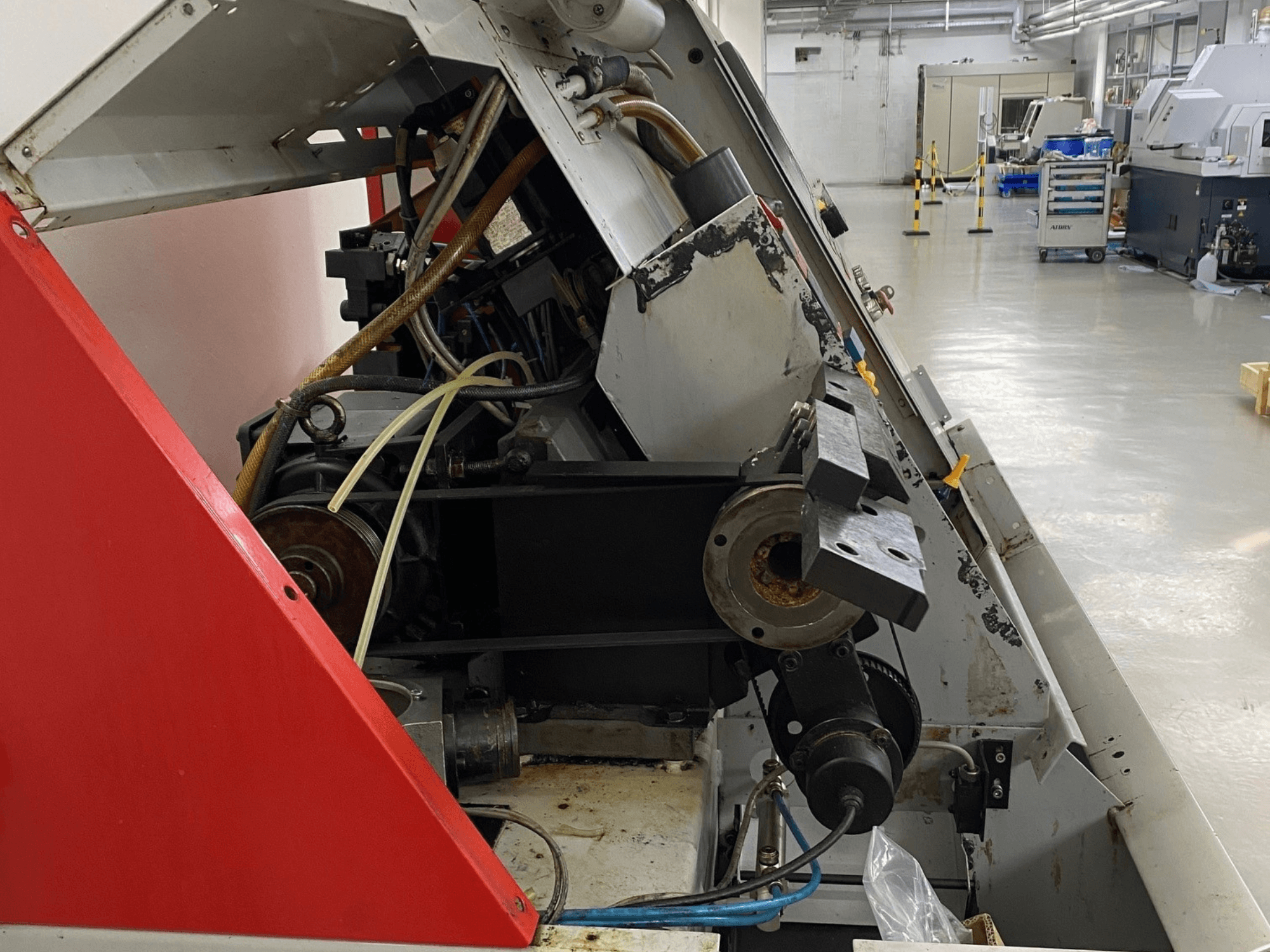 EMCO Emcoturn 325 vaakasuuntainen sorvauskone, sivukuva, jossa näkyy voimansiirtokomponentit ja hydrauliikka teollisuusympäristössä.