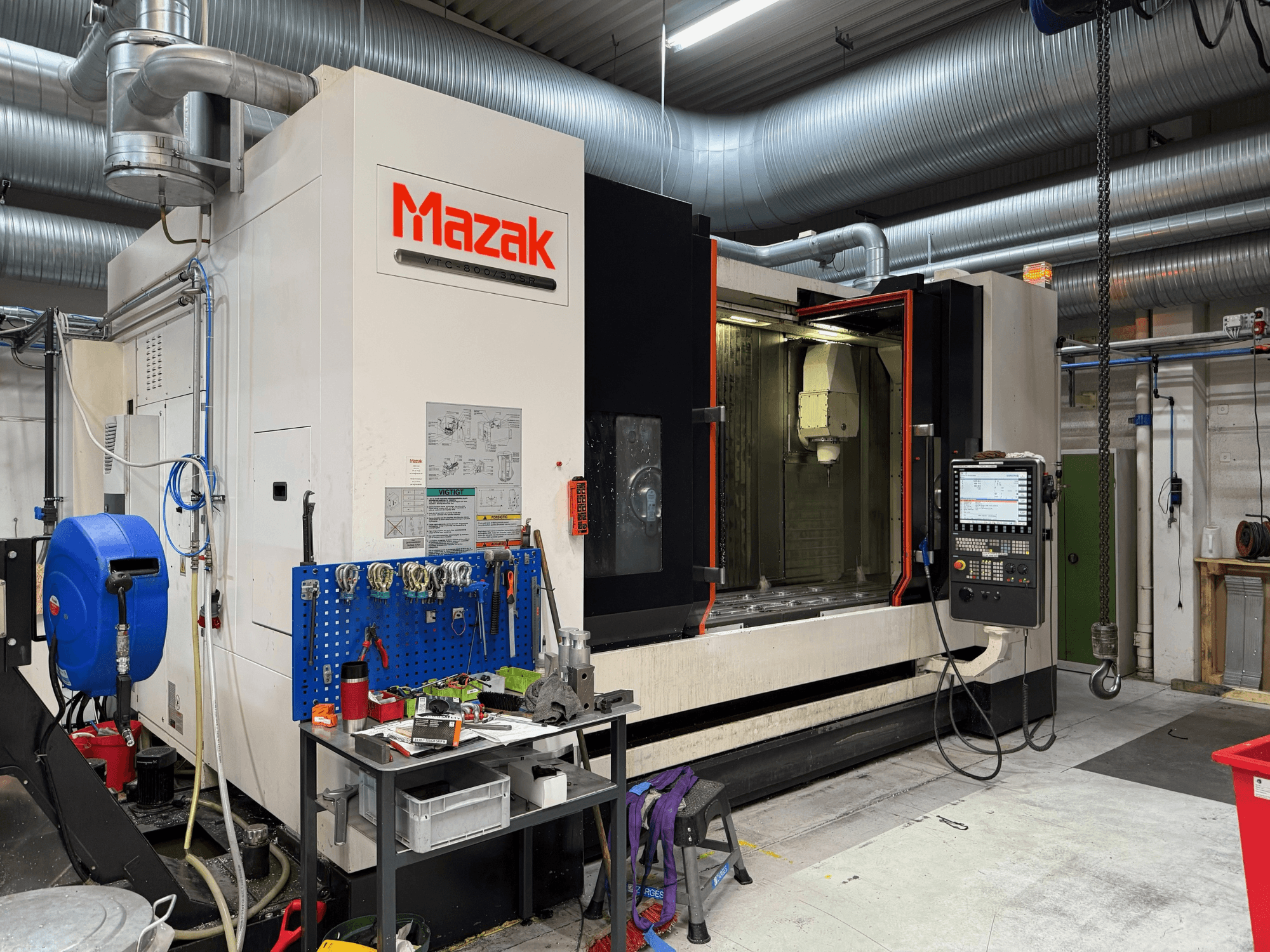 Mazak CNC-kone edestä katsottuna, jossa on ohjaimet, työkalut ja työtila koneistusympäristössä.