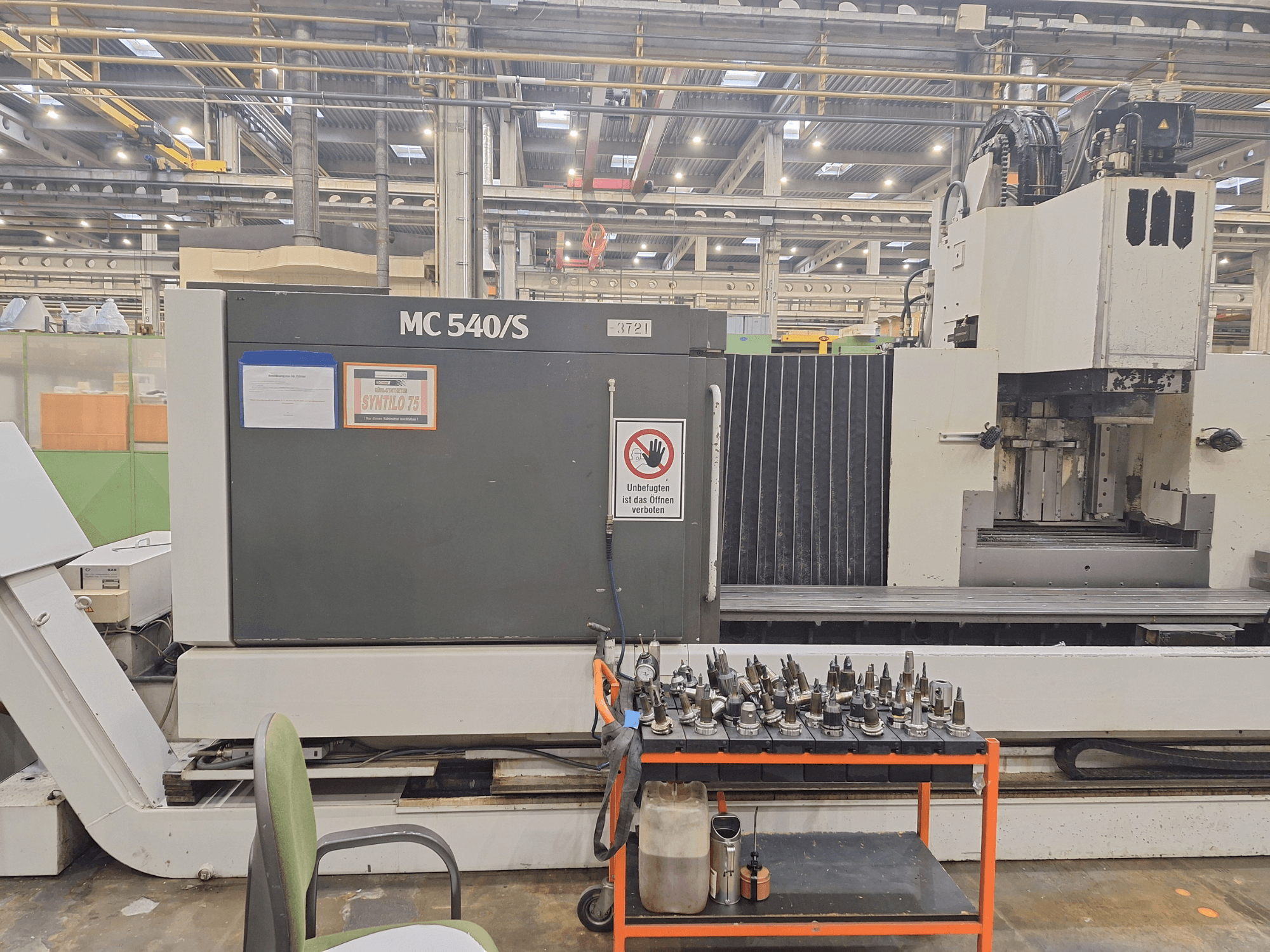 Pystytyöstökeskus STAMA MC 540S työpajassa, sivukuva, työkalunpitimet kärryllä vieressä.