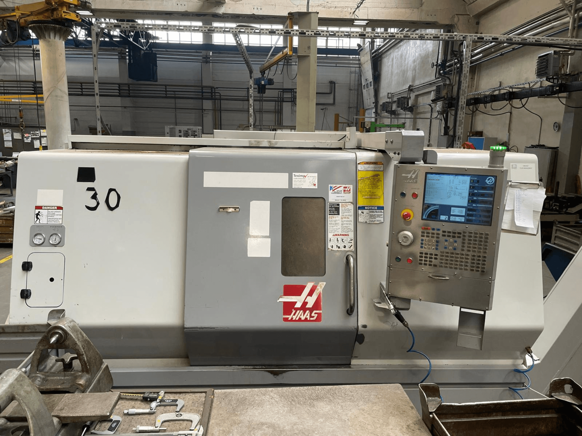 Haas SL-30THE -vaakasuoran sorvin etunäkymä, jossa näkyy digitaalinen ohjauspaneeli, varoitusmerkinnät ja mallinumero 30.