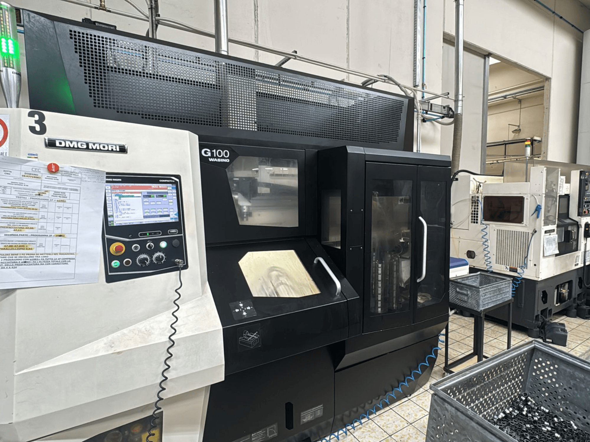 DMG MORI G100 -kone tehtaalla, etukuva, jossa on digitaalinen ohjauspaneeli ja läheiset työkalujen säilytyslaatikot.