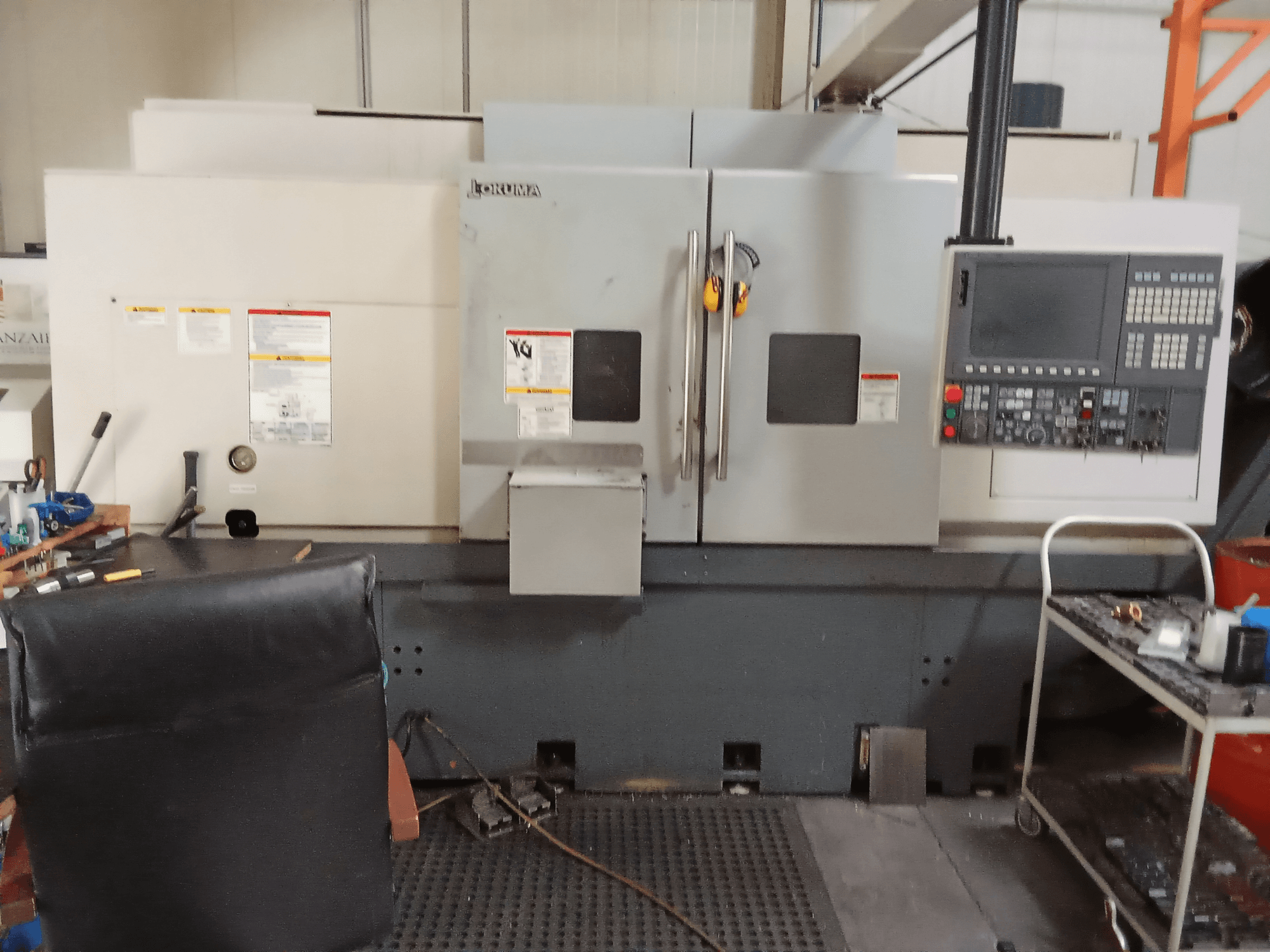 Okuma Genos L300 E-M -vaakasorvauskone edestä katsottuna, jossa on ohjauspaneeli ja kaksoisovet, työpajaympäristössä.
