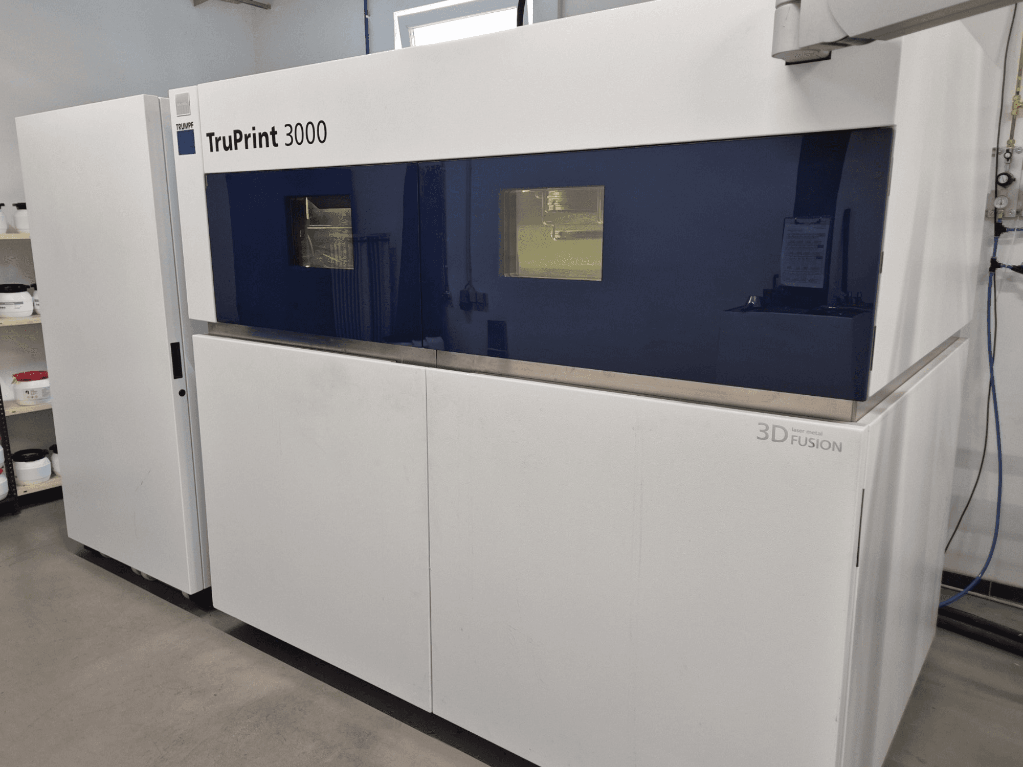 TruPrint 3000 -metalli-3D-tulostin etukuvassa, jossa on sinipintainen muotoilu ja laserfuusiotekniikka.
