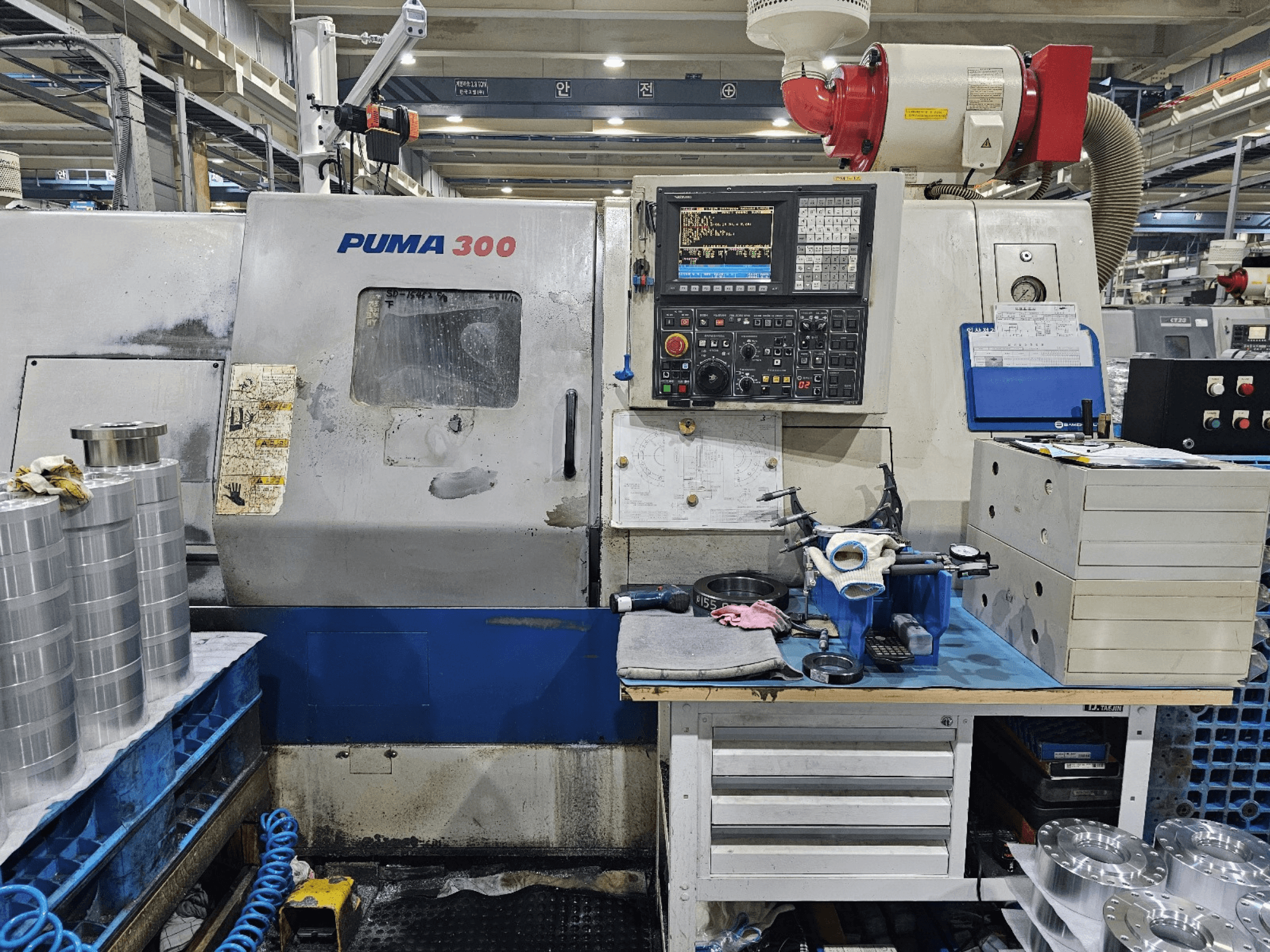 PUMA 300 CNC-kone työpajassa; etukuva, jossa näkyy ohjauspaneeli, työkaluja ja metalliosia työpöydällä.