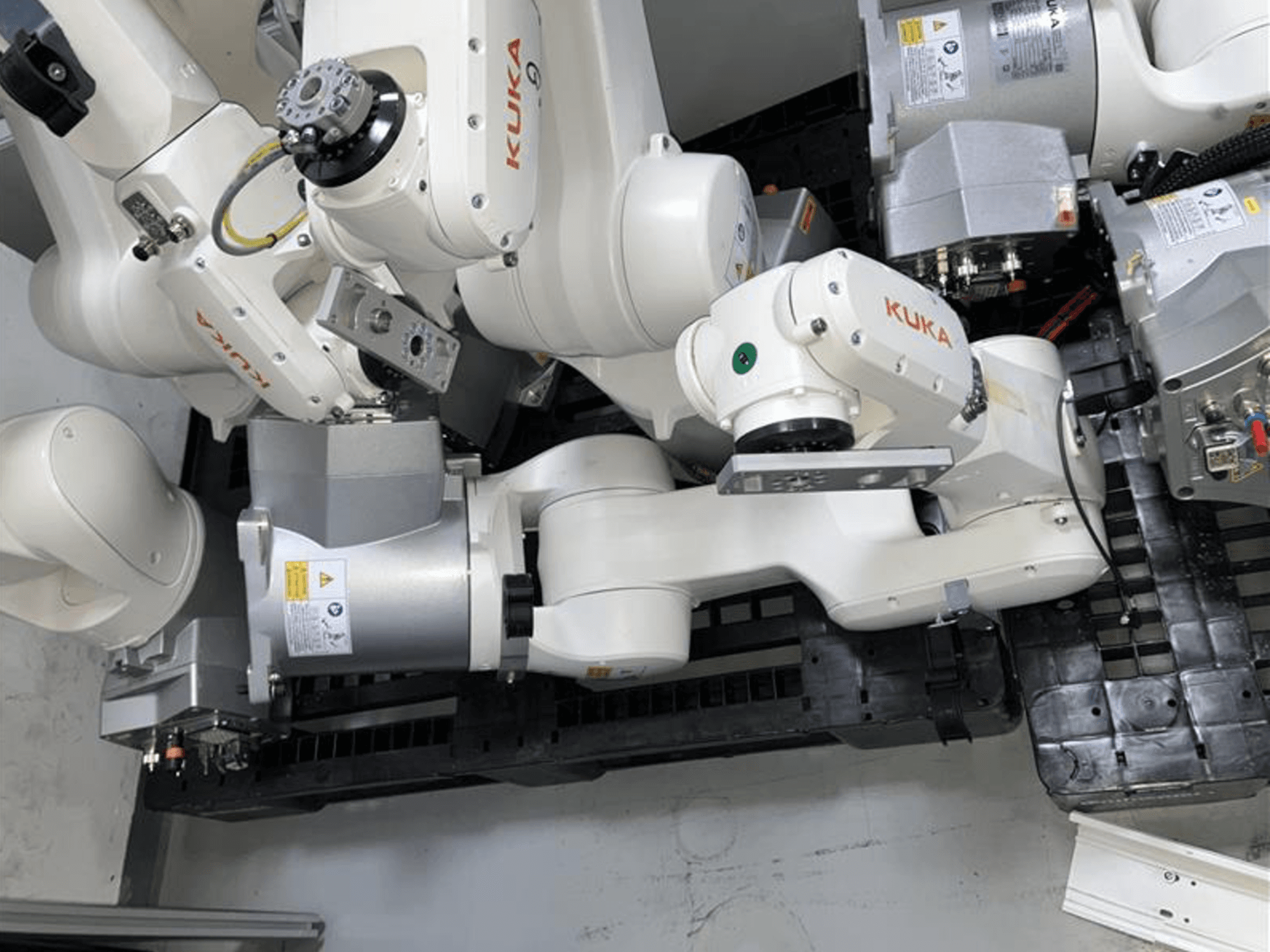 KUKA KR 6 R900 CR -robottivarsi ylhäältä katsottuna, jossa on useita niveliä ja moottoreita ja joka on asennettu mustalle jalustalle kaapeleineen.