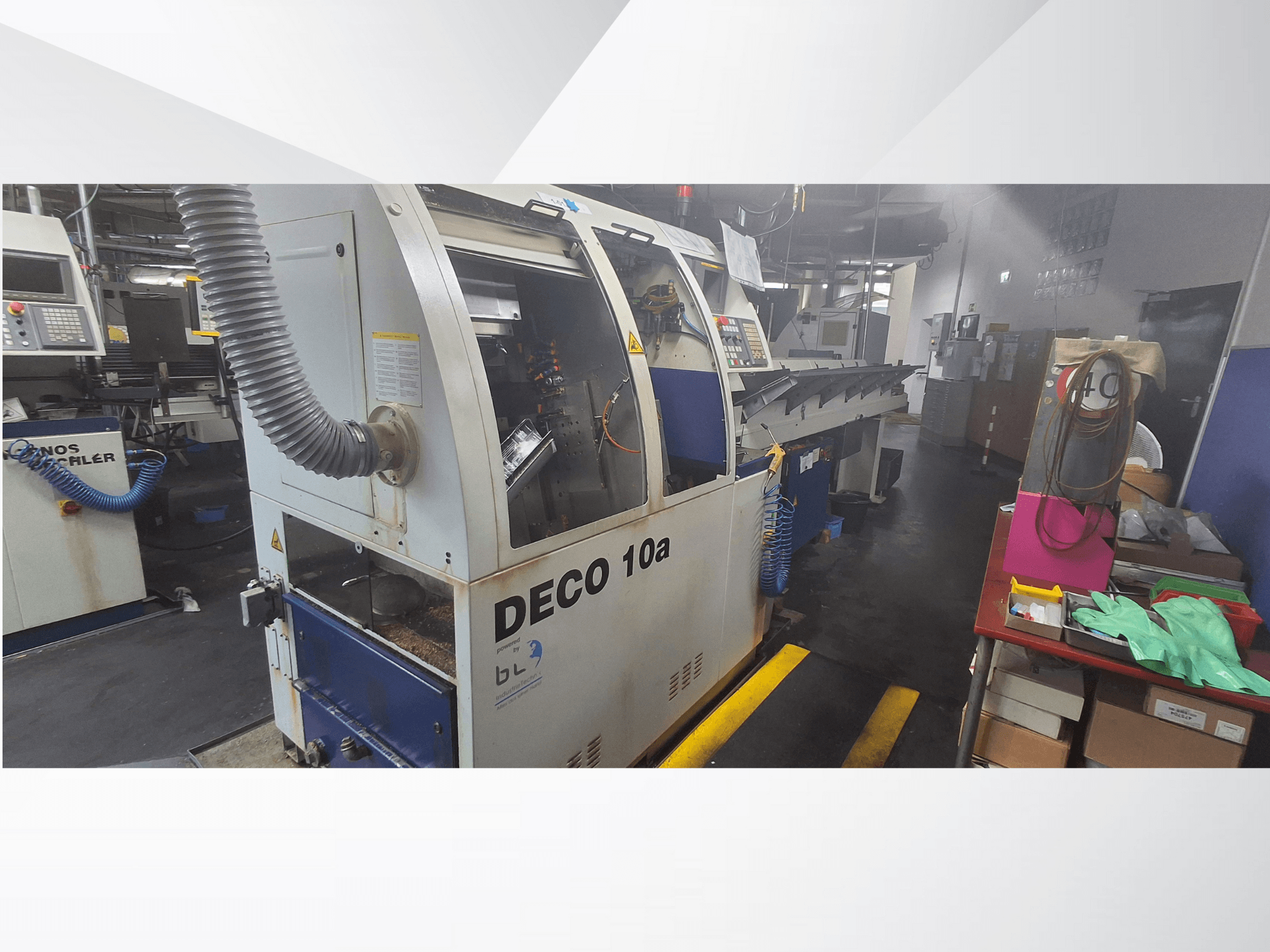 DECO 10a CNC-kone työpajassa, etukuva; ohjauspaneeli ja pölynpoistojärjestelmä, työpöytä lähellä.