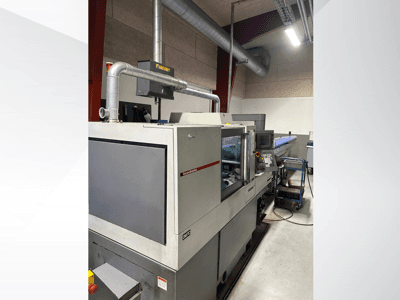 MVC-merkkinen teollisuuskone, sivukuva, jossa ohjauspaneeli ja kanavisto näkyvissä, tehdasympäristössä.