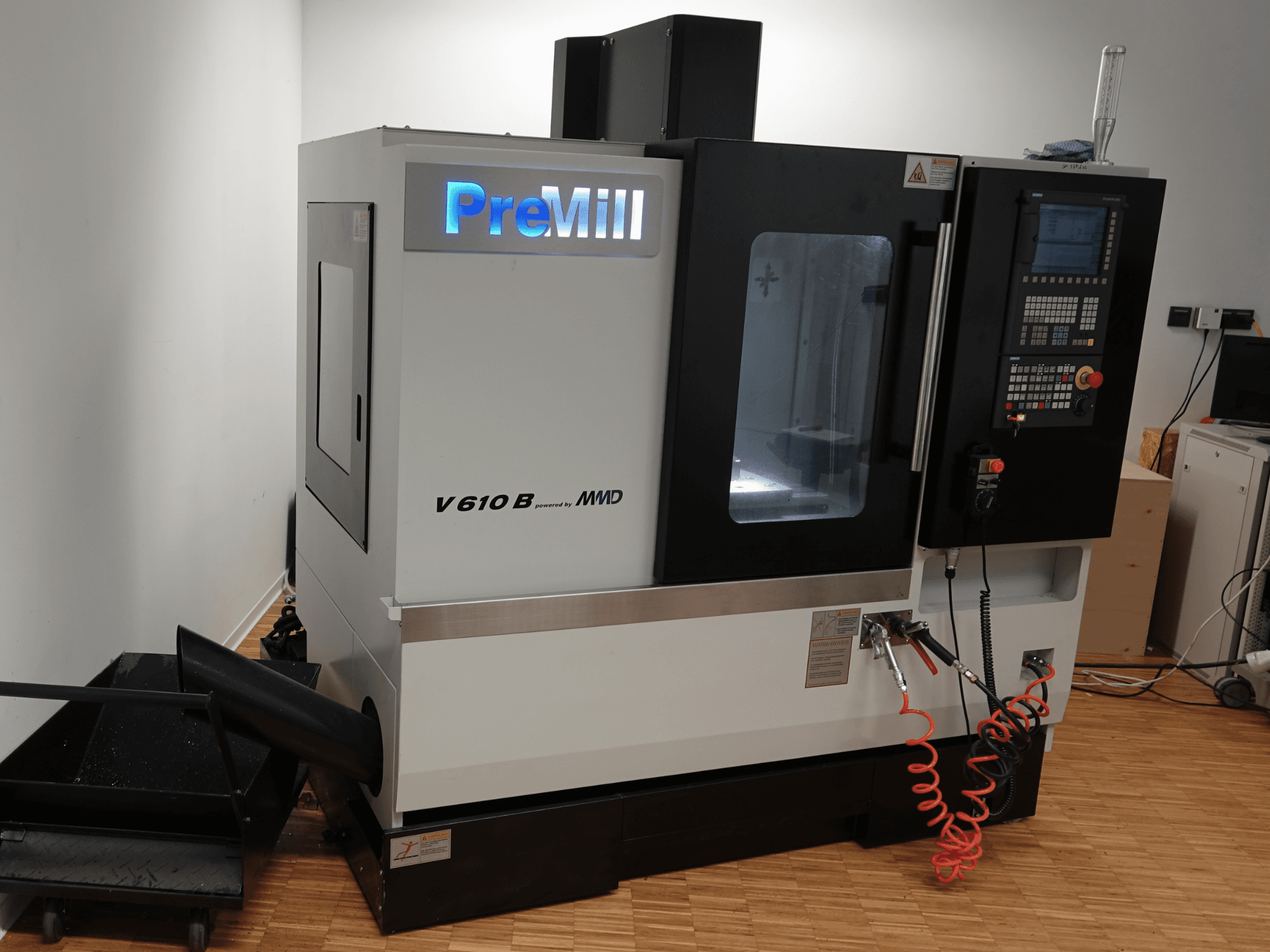 PreMill V 610 B -pystykoneistuskeskus, etunäkymä, jossa näkyvät ohjauspaneeli, jäähdytysnestejärjestelmä ja kiinnitetyt ilmaletkut.