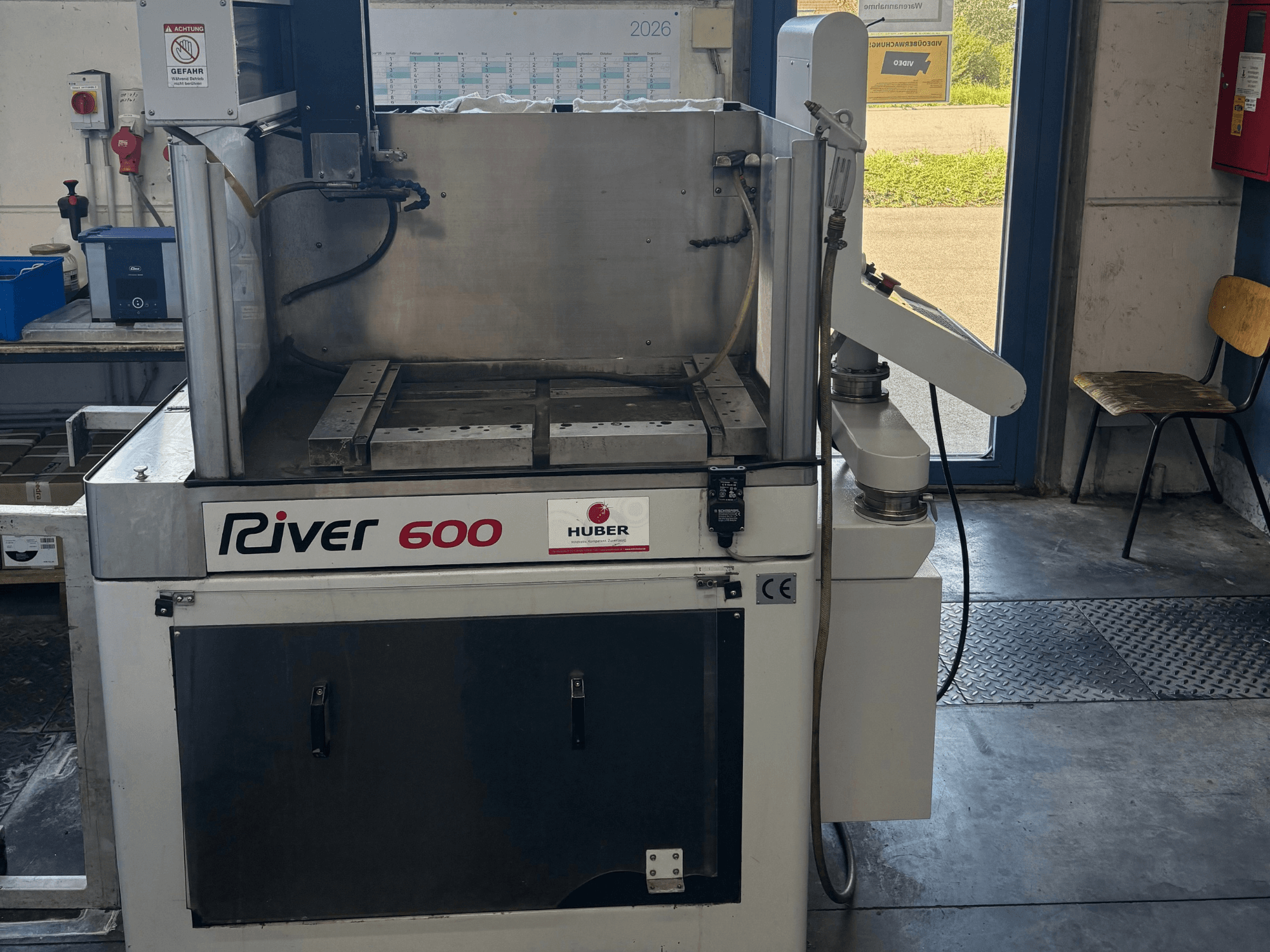 HUBER River 600 CNC-upotuskäyttöinen EDM-kone, etunäkymä, jossa näkyy osittain avoin työkammio ja ohjauspaneeli.