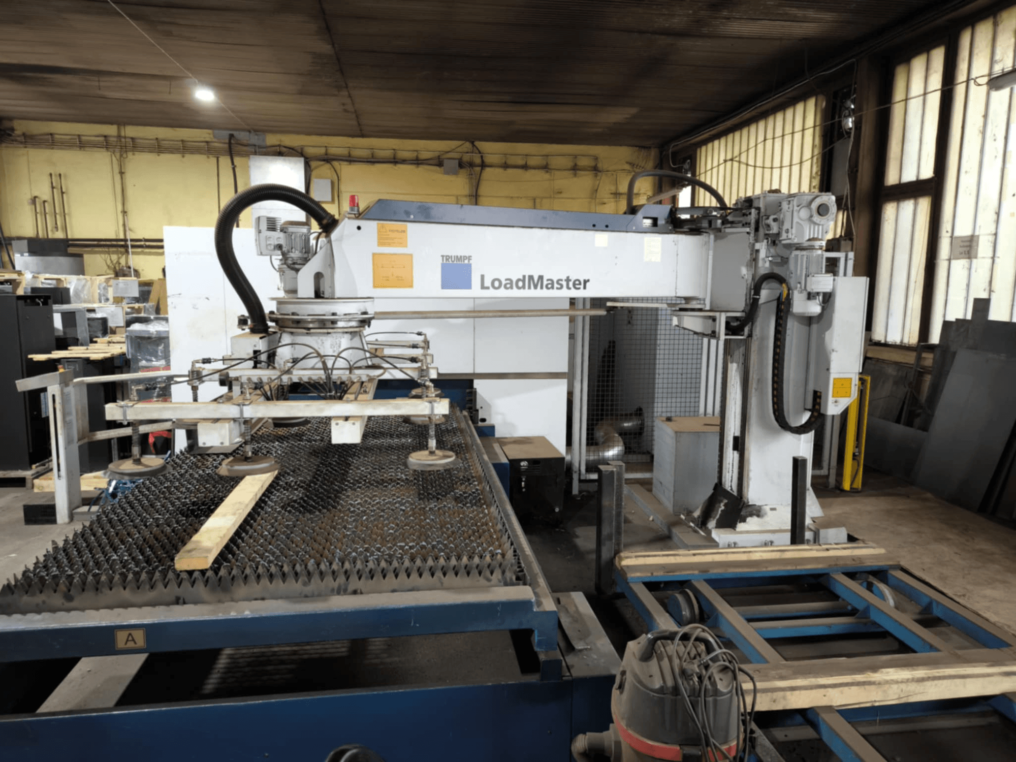 TRUMPF TRULASER 3030 FIBER -kuituleikkauskone, etukuva, jossa on LoadMaster-järjestelmä ja joka on sijoitettu ritilätyöpöydälle.