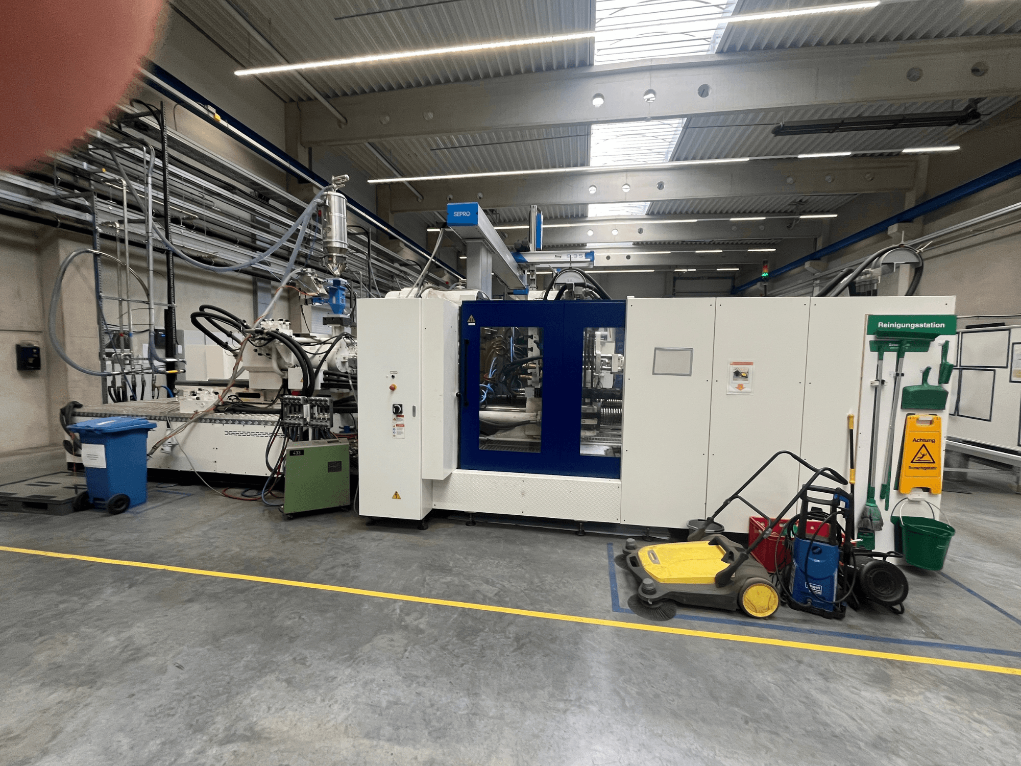 Teollisuuskone tehtaassa, etukuva, lähellä sinivalkoisia paneeleita, letkuja ja puhdistuslaitteita.
