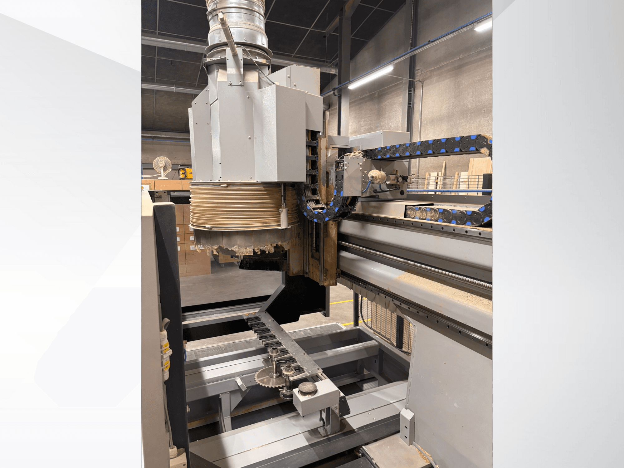 CNC-jyrsinkone, jossa on suuri kara ja kuljetin, sivukuva, jossa on puunleikkaustyökaluja ja koneen osia.