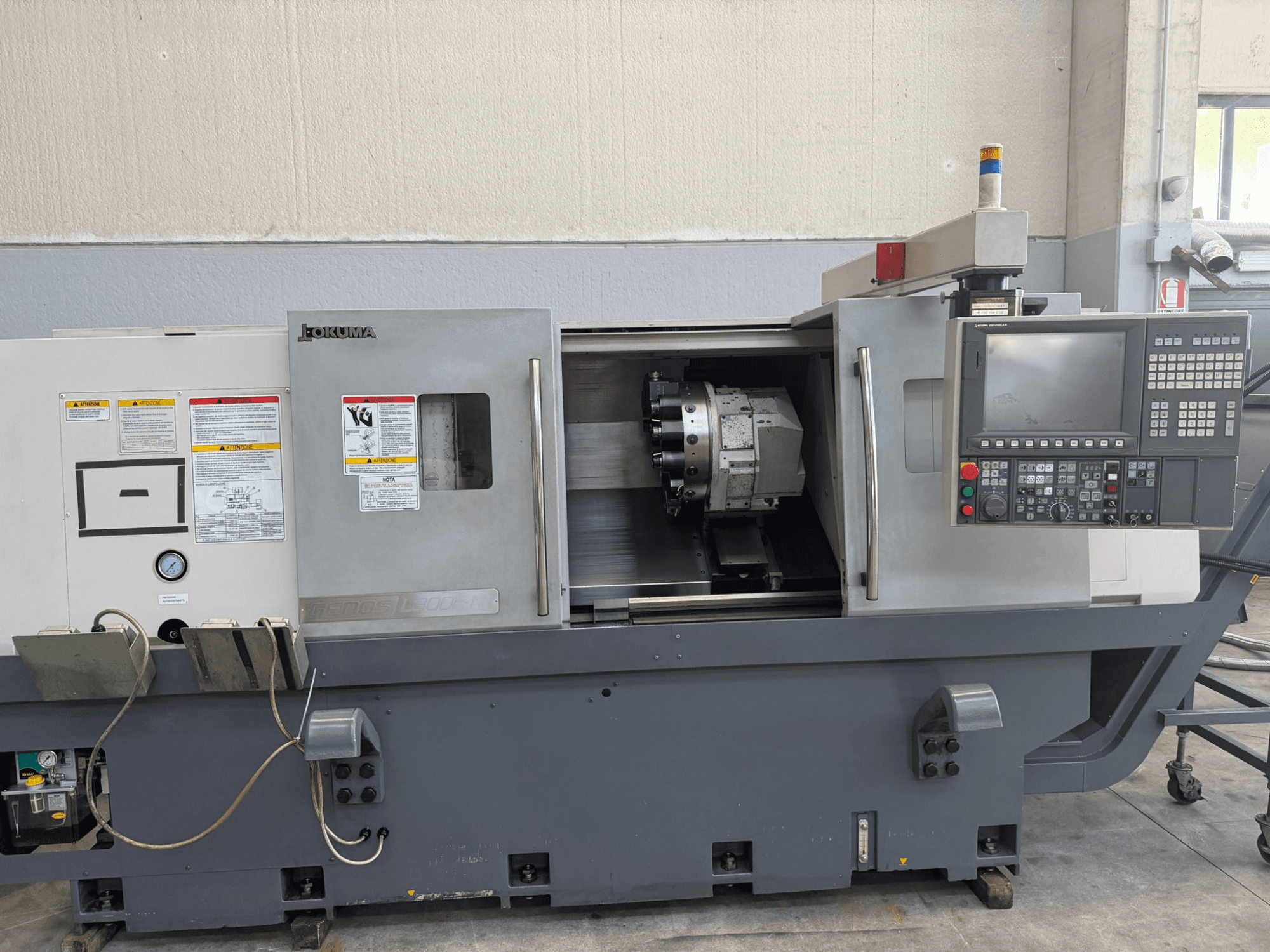 Okuma CNC-sorvi, etukuva, jossa näkyy ohjauspaneeli, leikkuutyökalun pidike ja sivussa olevat turvallisuusvaroitukset.