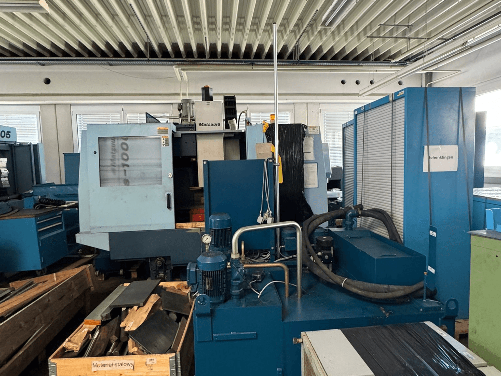 Matsuura Vplus 1000/40 -pystykoneistuskeskukseista otettu etunäkymä, jossa näkyvät ohjauslaitteet, moottorit ja ympäröivä työpaja-ympäristö.