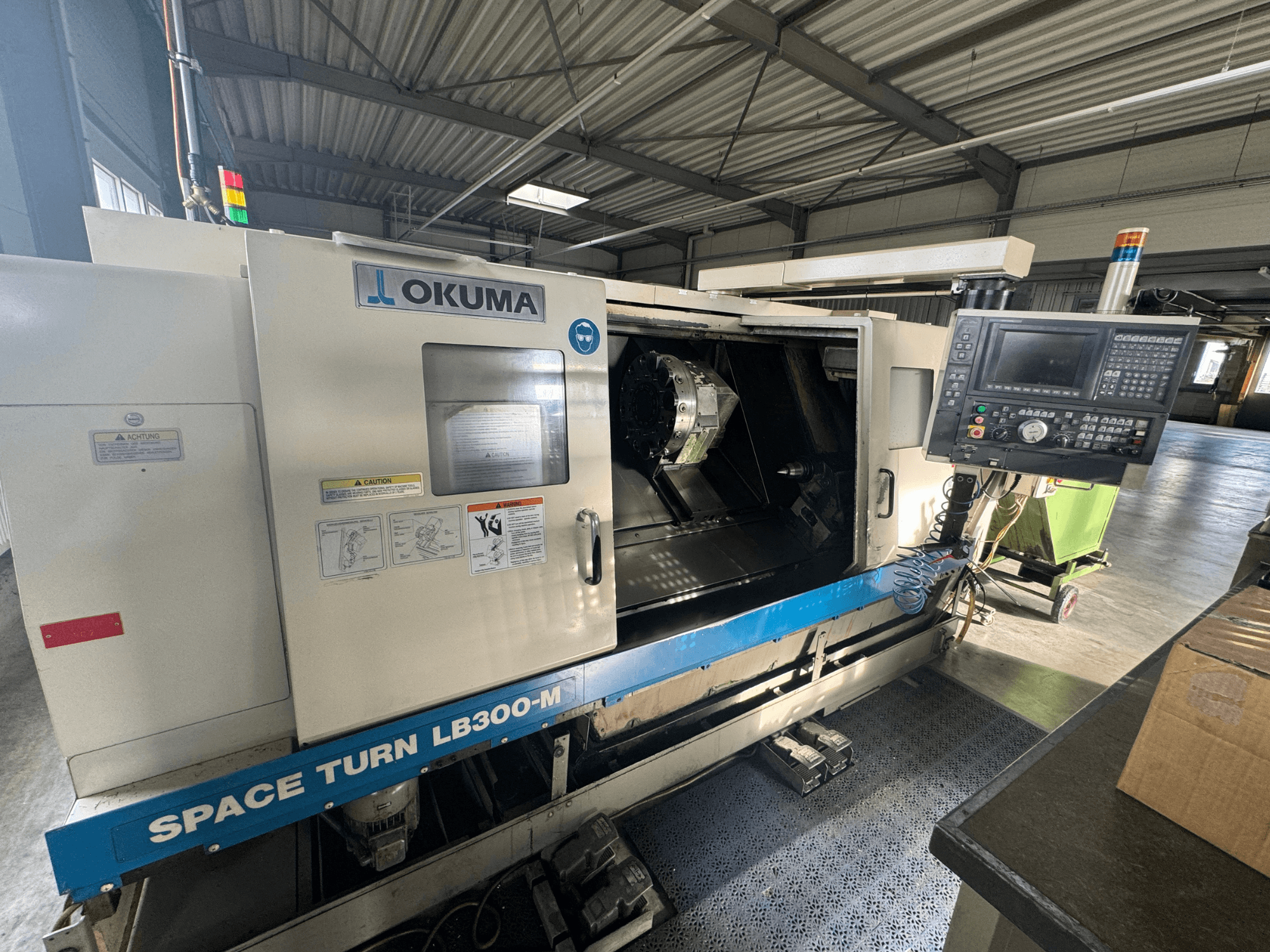 Okuma Space Turn LB300-M CNC-sorvi etukuvassa, jossa on ohjauspaneeli ja avoin ovi, joka paljastaa sisätyöstöalueen.