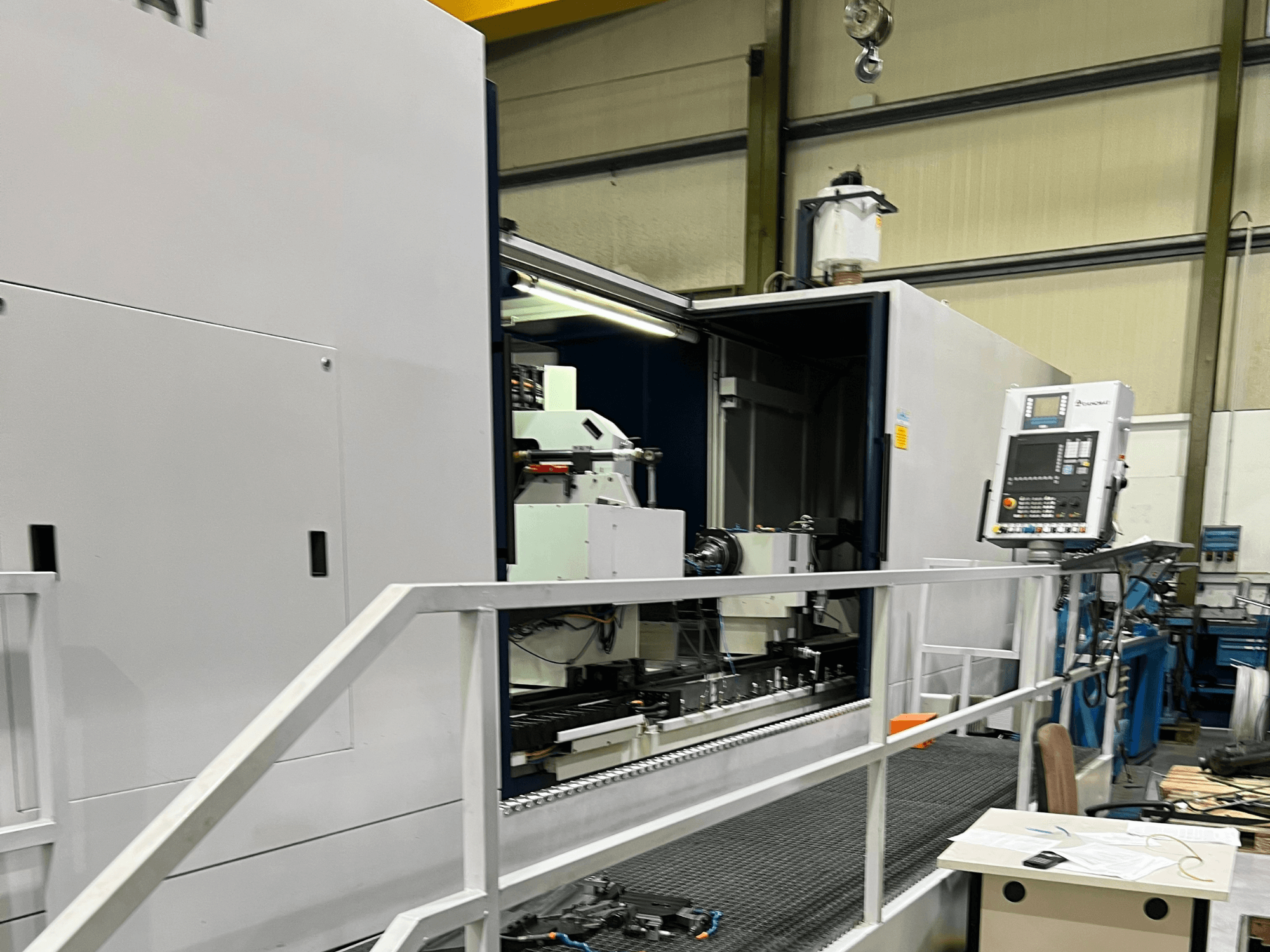 CNC-työstökeskus avoimessa sivukuvassa, jossa näkyvät hallintalaitteet, työkalunpidin ja pääkomponentti sisällä. Tuotemerkin tiedot eivät ole näkyvissä.