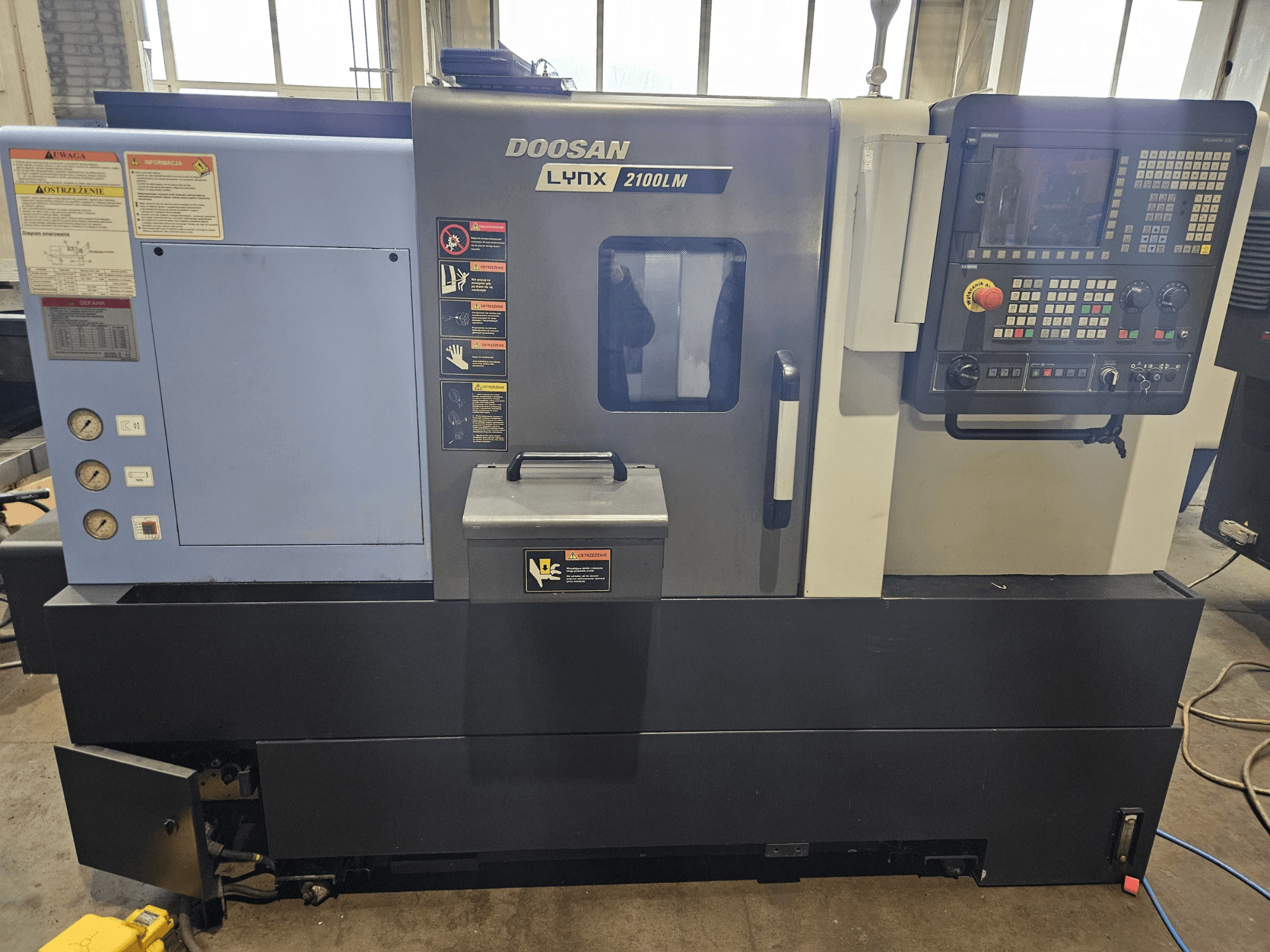 Doosan Lynx 2100LM CNC-sorvi, etukuva, jossa ohjauspaneeli, ilmanpainemittarit ja turvatarrat näkyvissä.