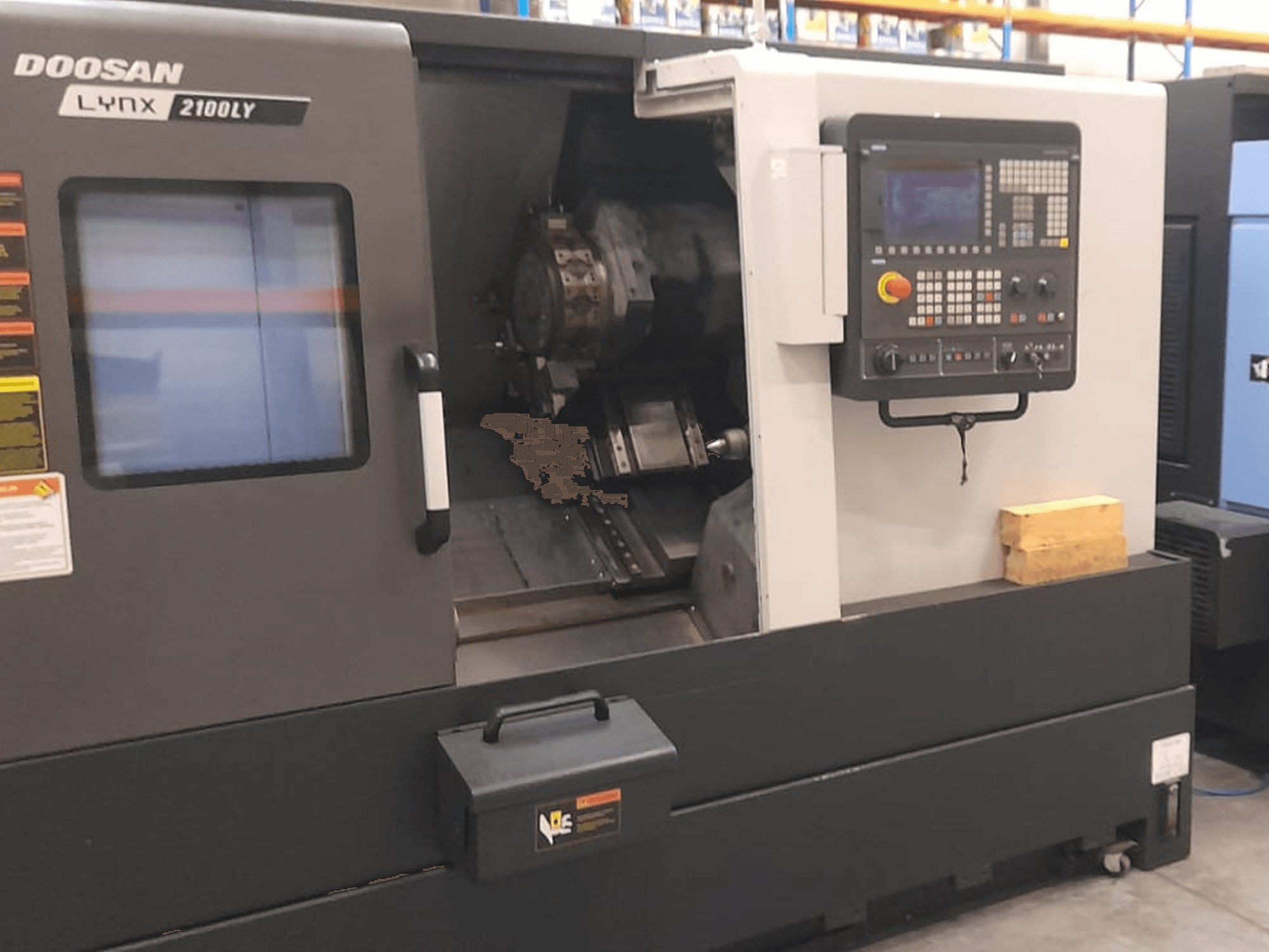 Doosan Lynx 2100LY CNC-sorvi, etukuva, jossa näkyy ohjauspaneeli, työkalunpidin ja sisätyötila; tekniset merkinnät näkyvissä.