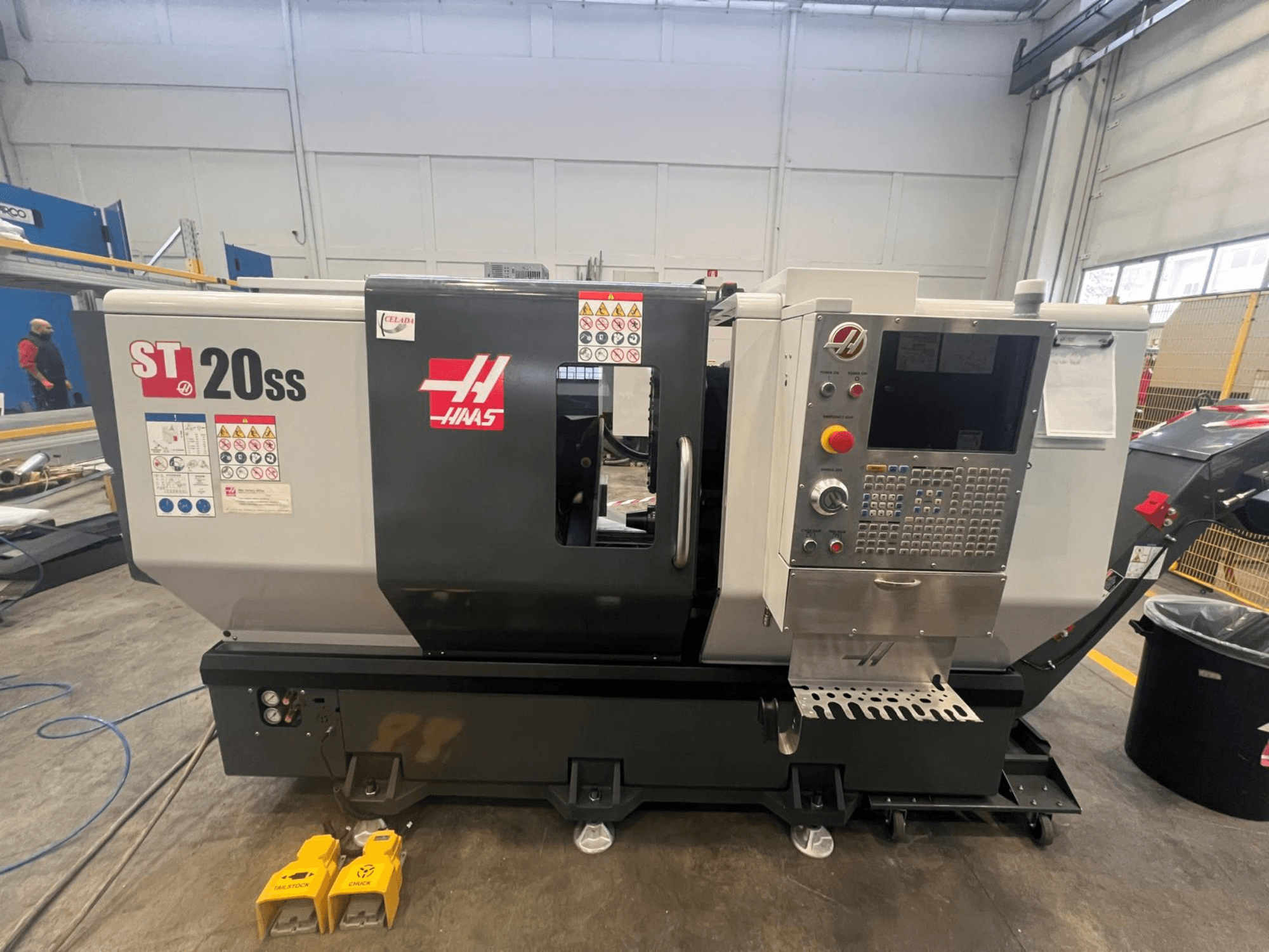 Haas ST 20SS CNC-sorvi sivukuvassa, jossa ohjauspaneeli, turvatarrat ja jalkapolkimet lattialla.