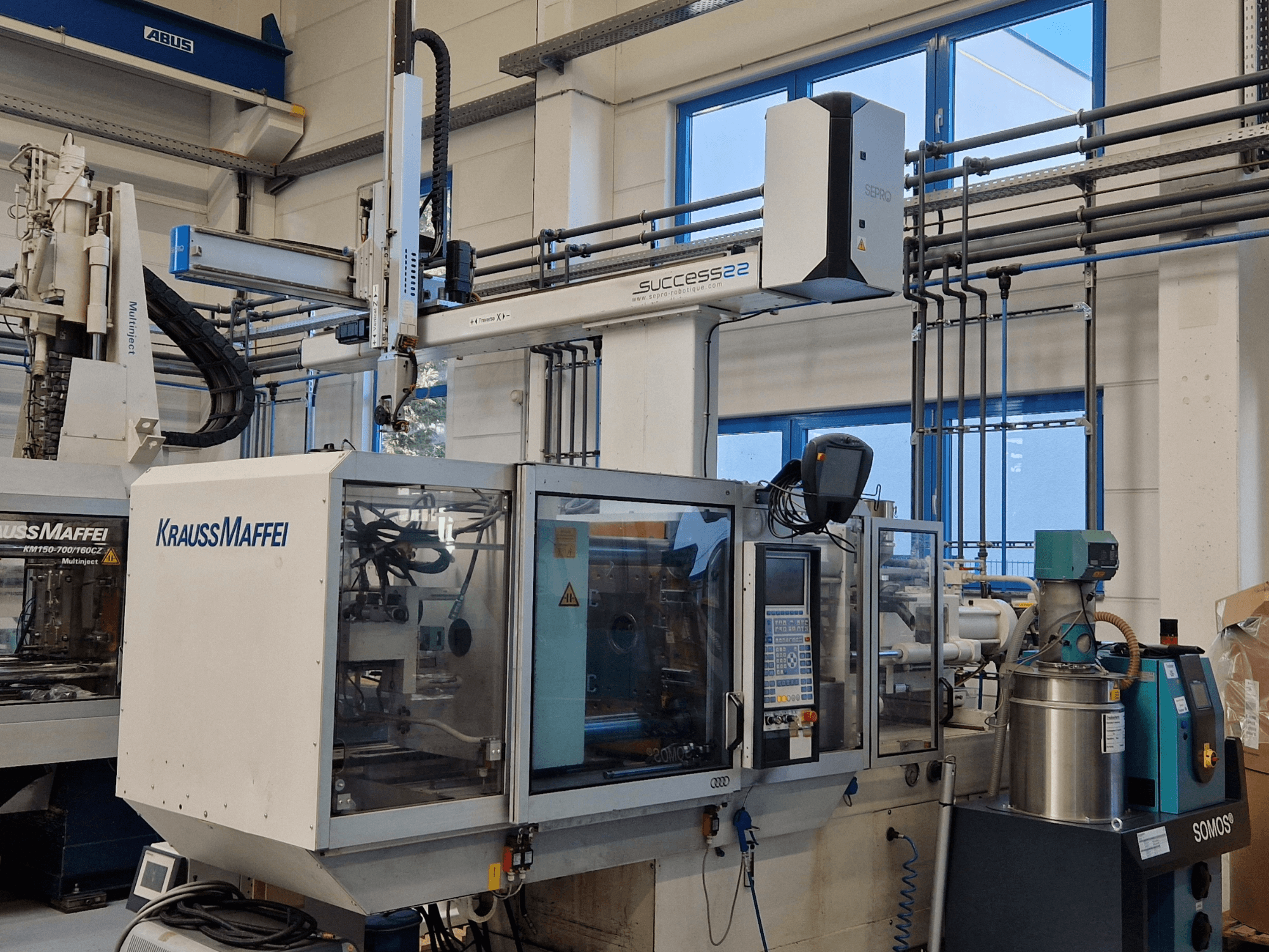 KraussMaffei Success 22 -ruiskuvalukone ja ohjauspaneeli edestä katsottuna tehtaalla.