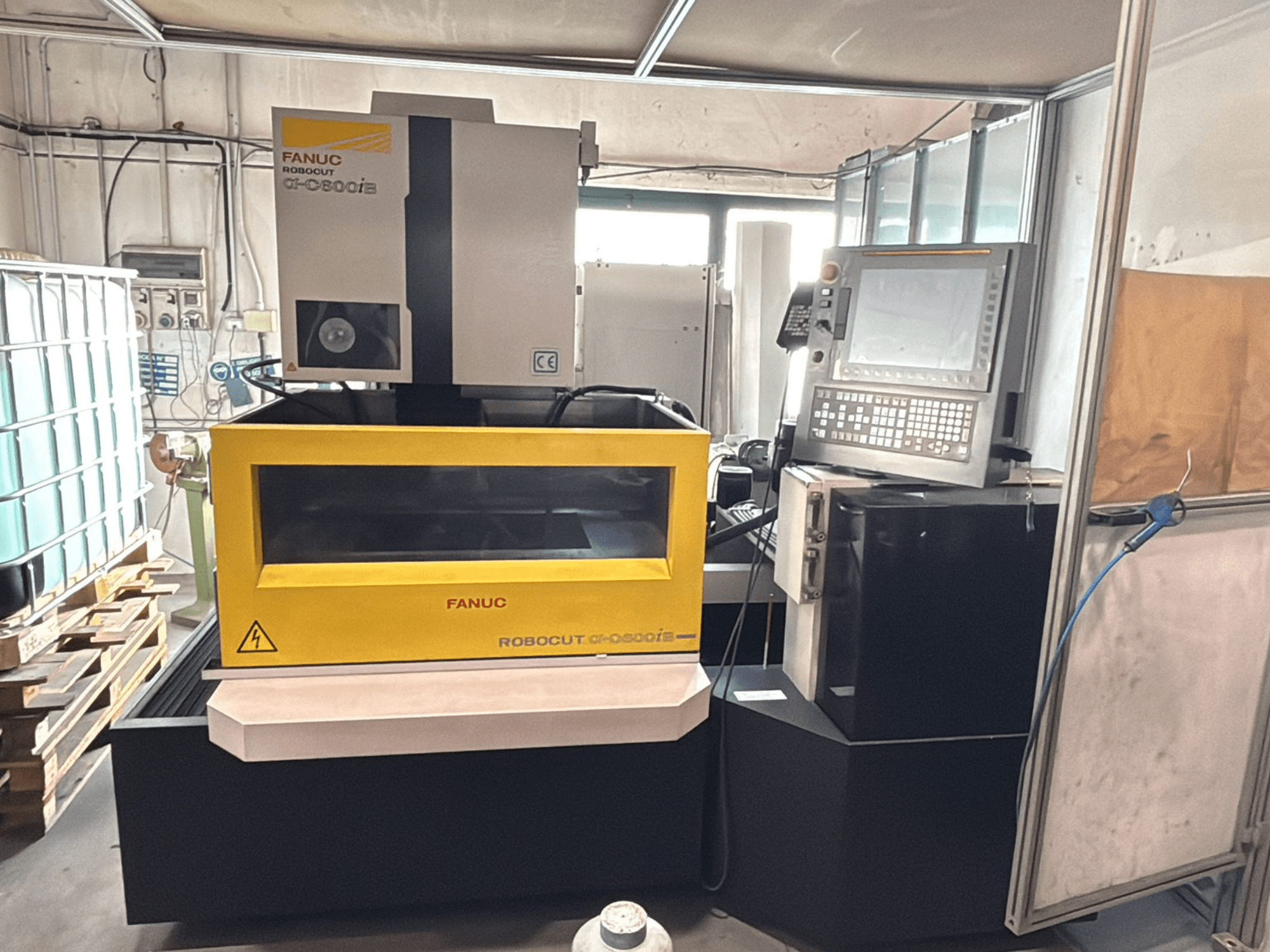 Etukuva FANUC Robocut α-0iE CNC-koneesta, jossa on keltainen kotelo ja jossa näkyy ohjauspaneeli ja näyttö.