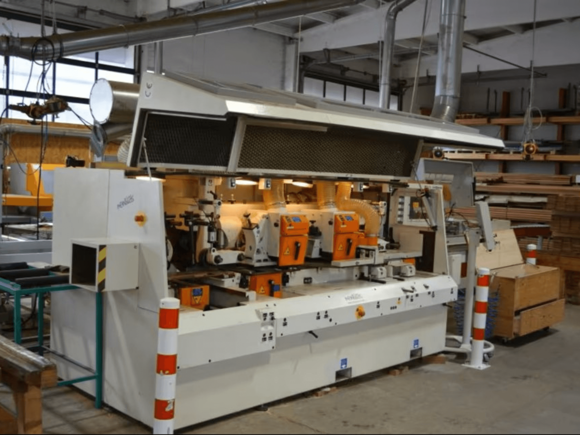 PENIGAS-puunjalostuskone, etukuva, jossa on kaksi oranssia leikkuupäätä ja pölynpoistojärjestelmä työpajassa.