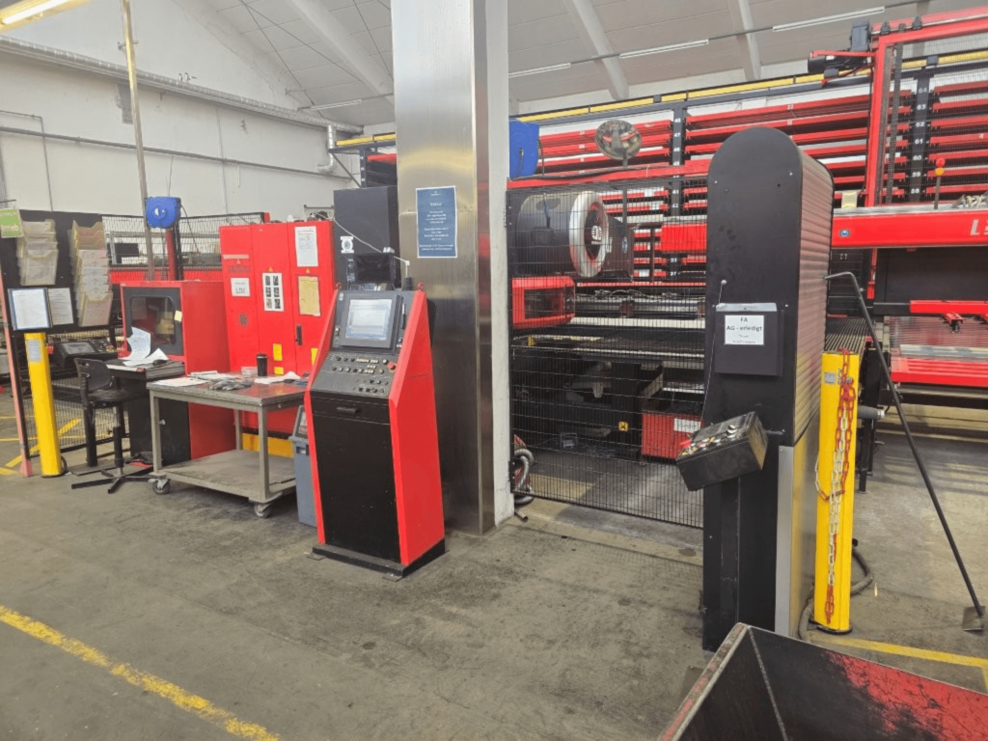 AMADA EMZ 3610 NT -CNC-lävistyskoneen etunäkymä, jossa näkyvät käyttölaitteet ja turvakotelo tehdasasennuksessa.