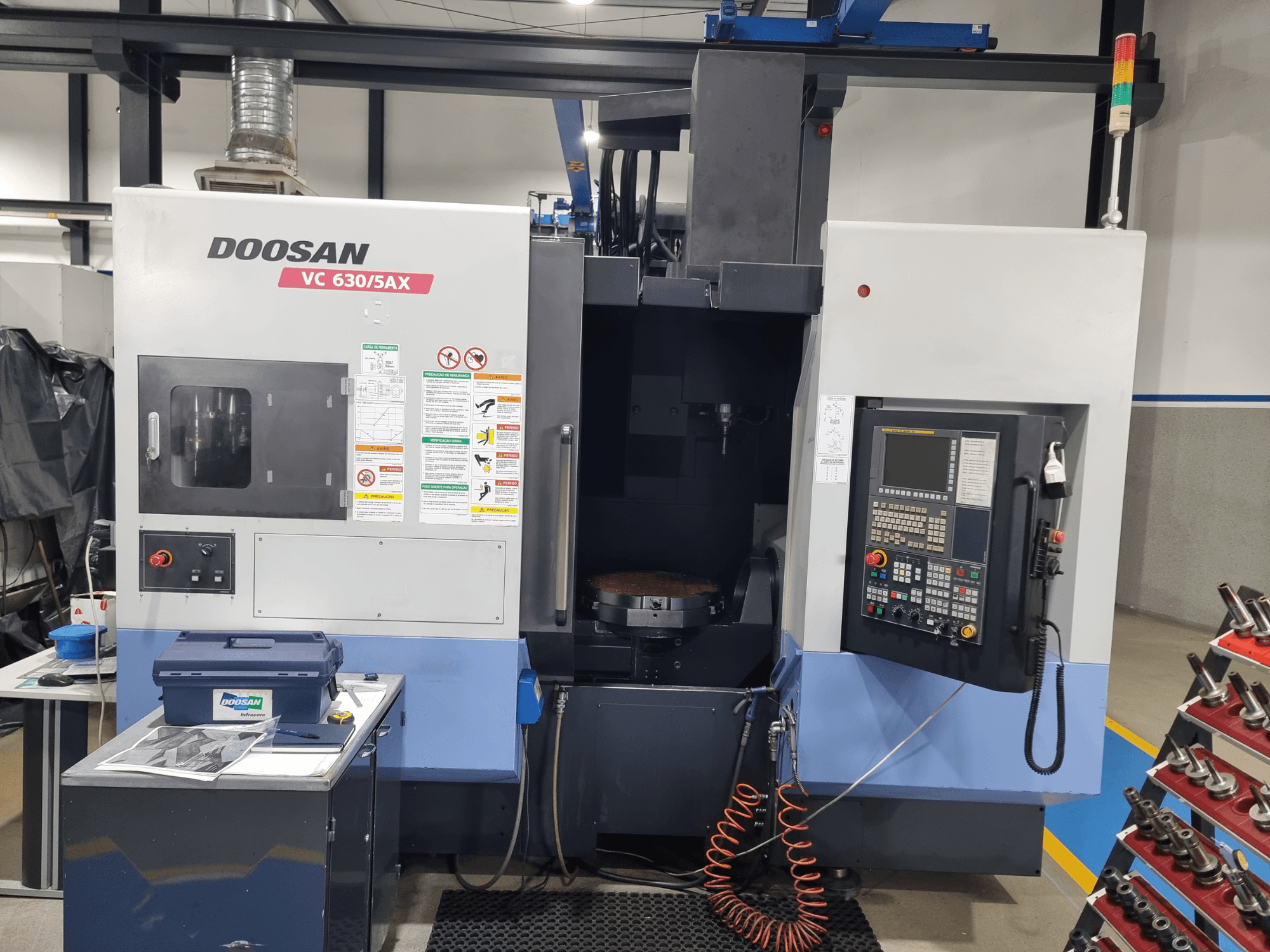 DOOSAN VC 630/5AX -yleiskoneistuskeskus, etunäkymä, jossa näkyvät ohjauspaneeli, työstöalue ja turvallisuusominaisuudet.
