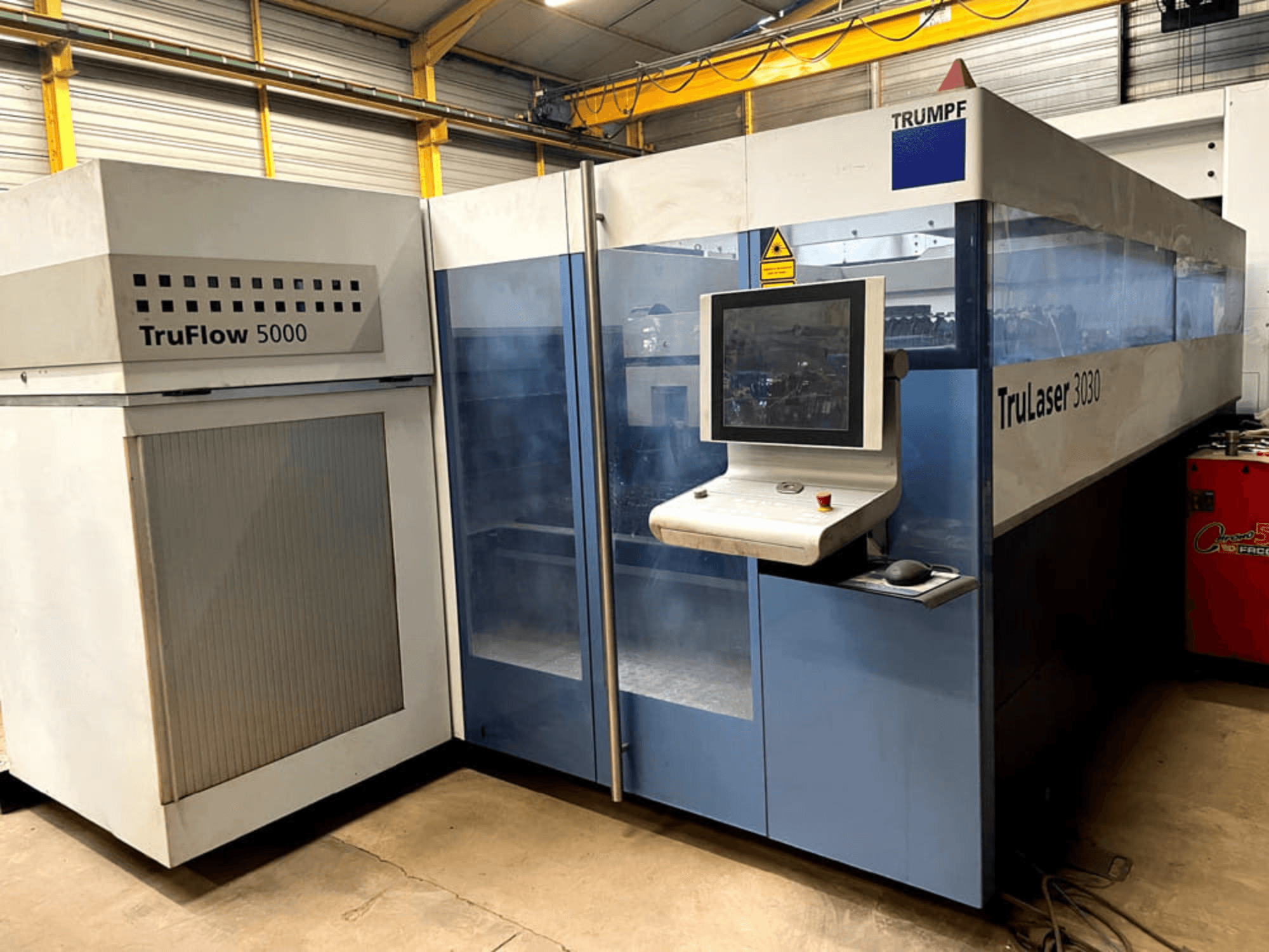 TRUMPF TruLaser 3030 CO₂-laserleikkauskone edestä katsottuna; kuvassa näkyy ohjauspaneeli ja sen vieressä oleva TruFlow 5000 -yksikkö.