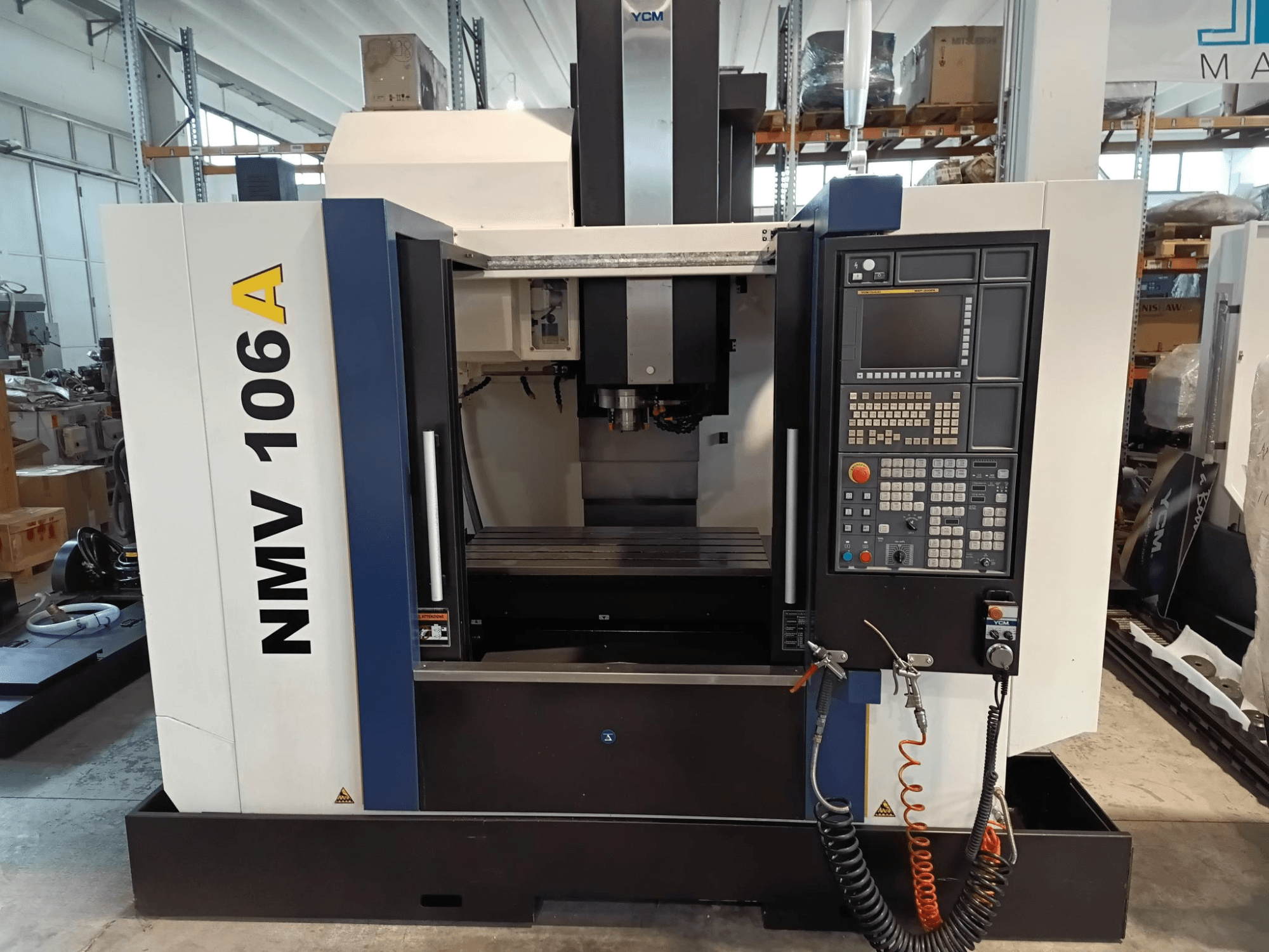 YCM NMV 106A -työstökeskus, etukuva, jossa on ohjauspaneeli painikkeineen ja jäähdytysnesteletkuineen.