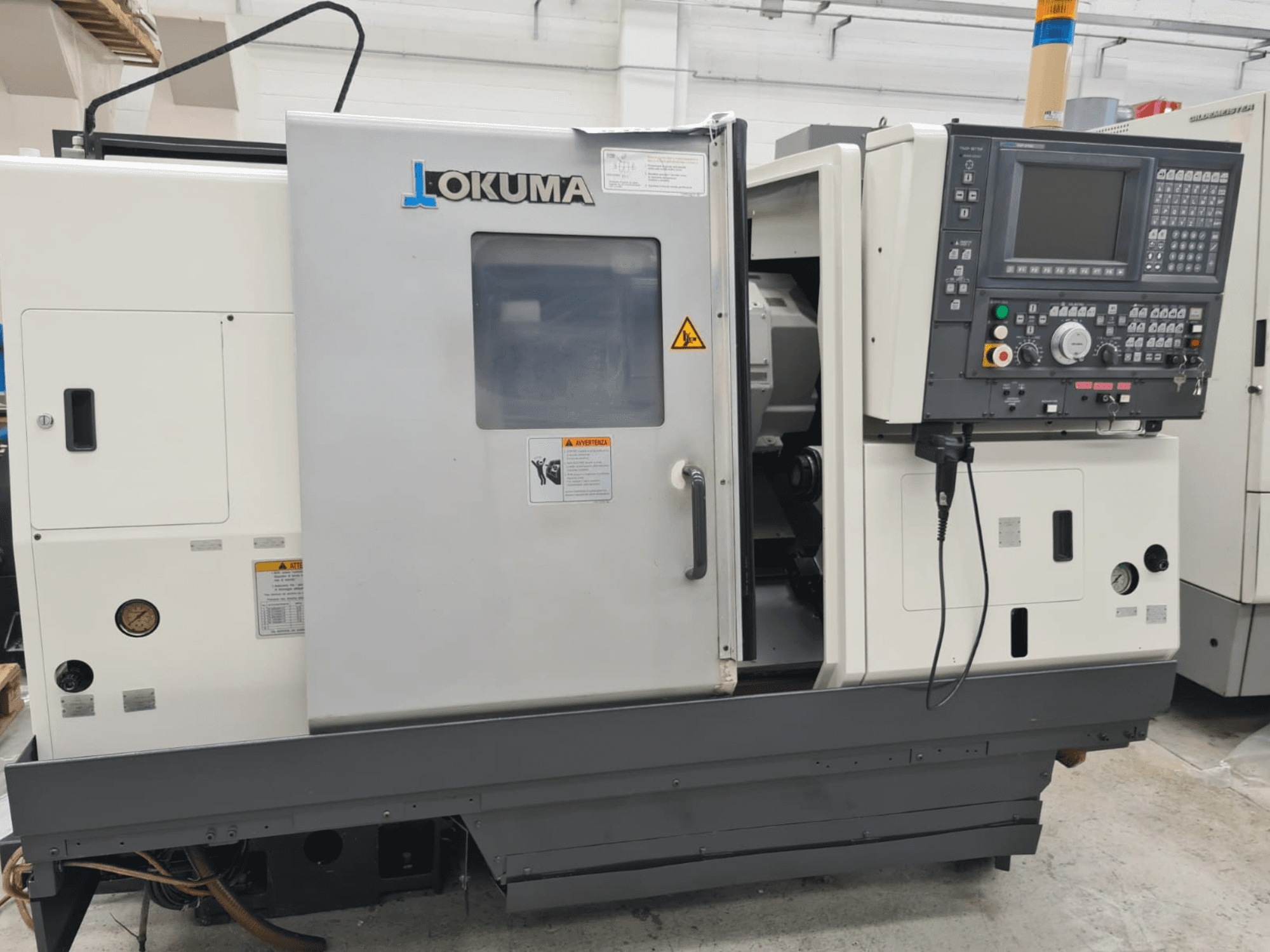 Okuma LB 300M X 500 -vaakasorvauskone sivukuvassa, jossa näkyy ohjauspaneeli, karan pääsy ja turvallisuusvaroitukset.