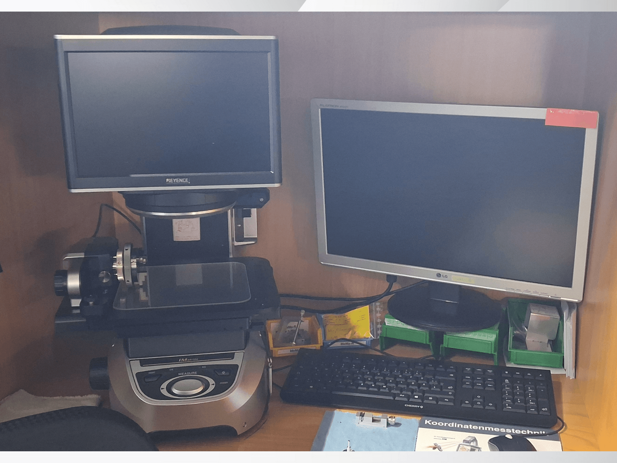 Keyence-mittausjärjestelmä, jossa on kaksi näyttöä (yksi LG, yksi Keyence) ja näppäimistö, edestä katsottuna.