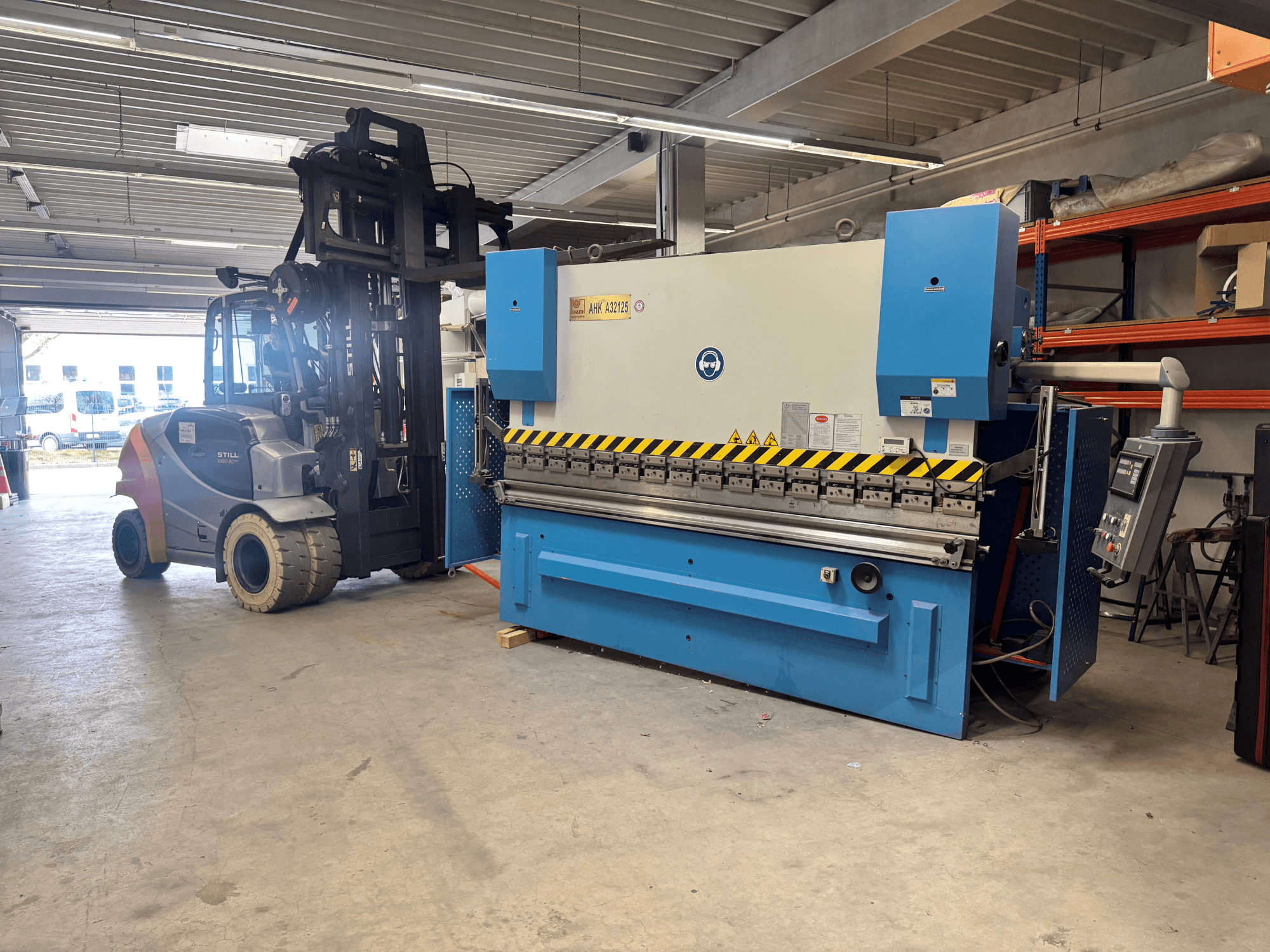 Hydraulinen puristin KNUTH AHK A 32125 työpajassa, sivukuva, jossa näkyy ohjauspaneeli ja turvaominaisuudet.