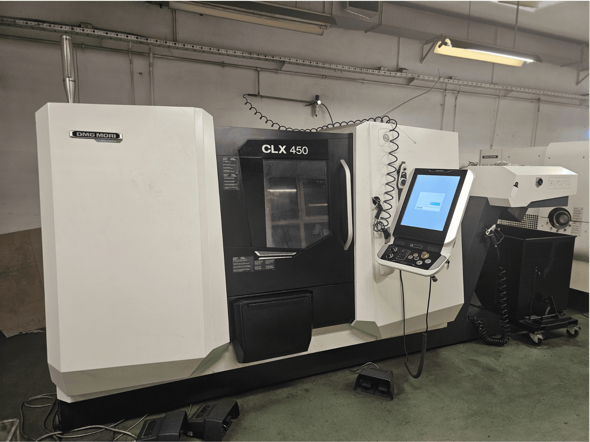 DMG MORI CLX 450 CNC-kone edestä katsottuna, jossa on ohjauspaneeli ja kosketusnäyttö, työpajaympäristössä.