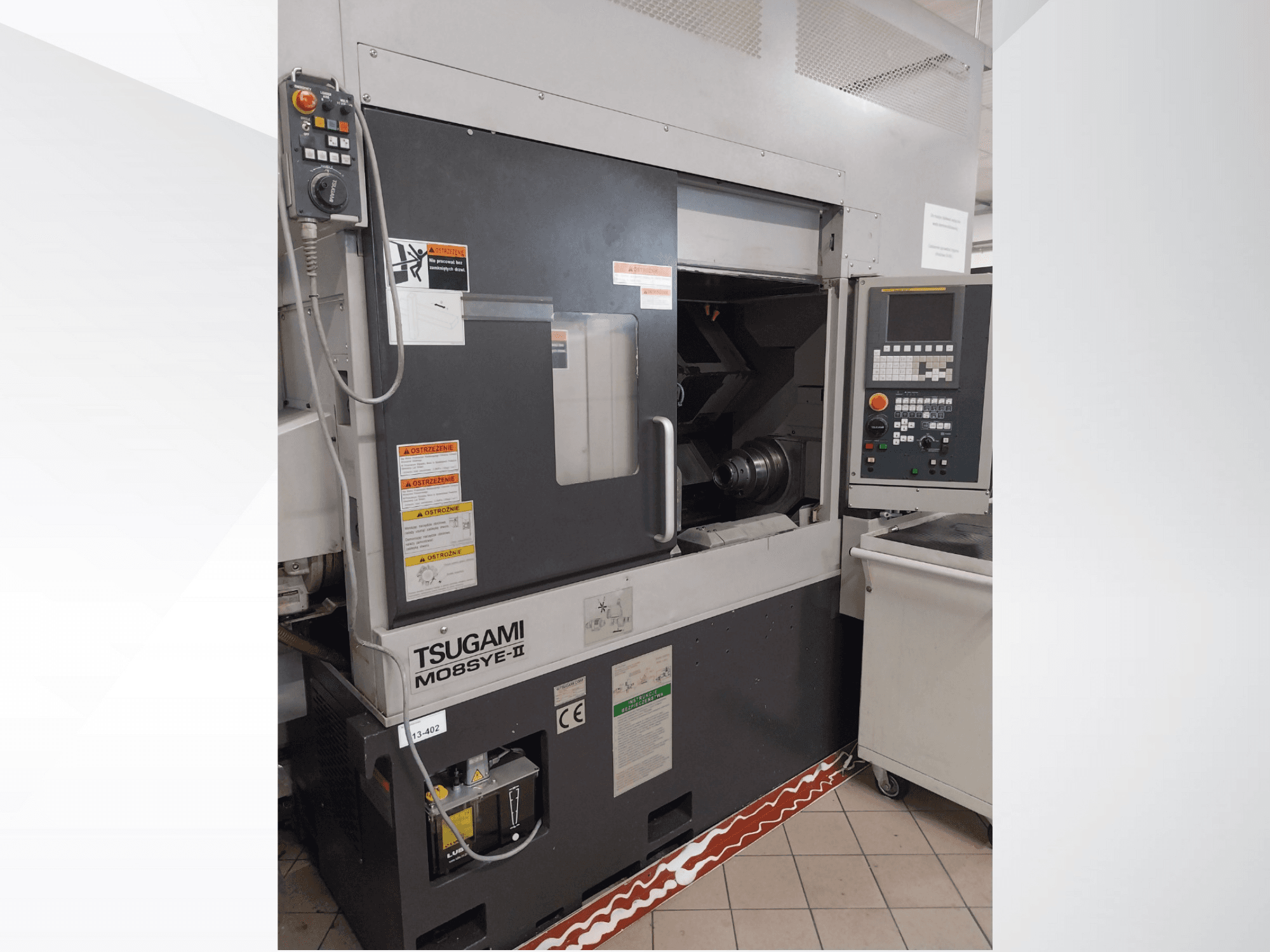 Tsugami M08SY-II CNC-sorvi, etukuva, jossa näkyy ohjauspaneeli, kara ja lastausalue. Mukana turvallisuusilmoitukset ja tuotemerkin etiketti.