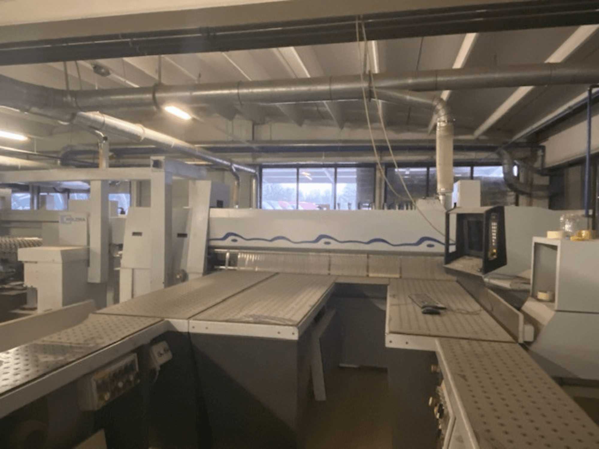 Teollinen työtila, jossa on koneasennus ja ohjauspaneeli, katsottuna kohotetusta etukulmasta.