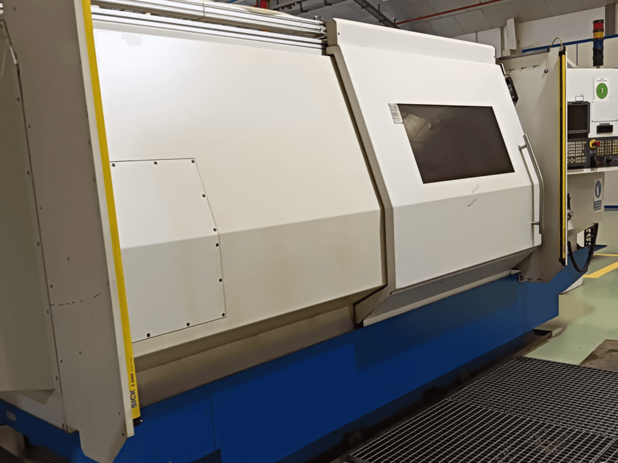 Teollisuussorvi sivukuvassa, jossa on suuri valkoinen ja sininen kotelo, digitaalinen ohjauspaneeli ja turvaominaisuudet.