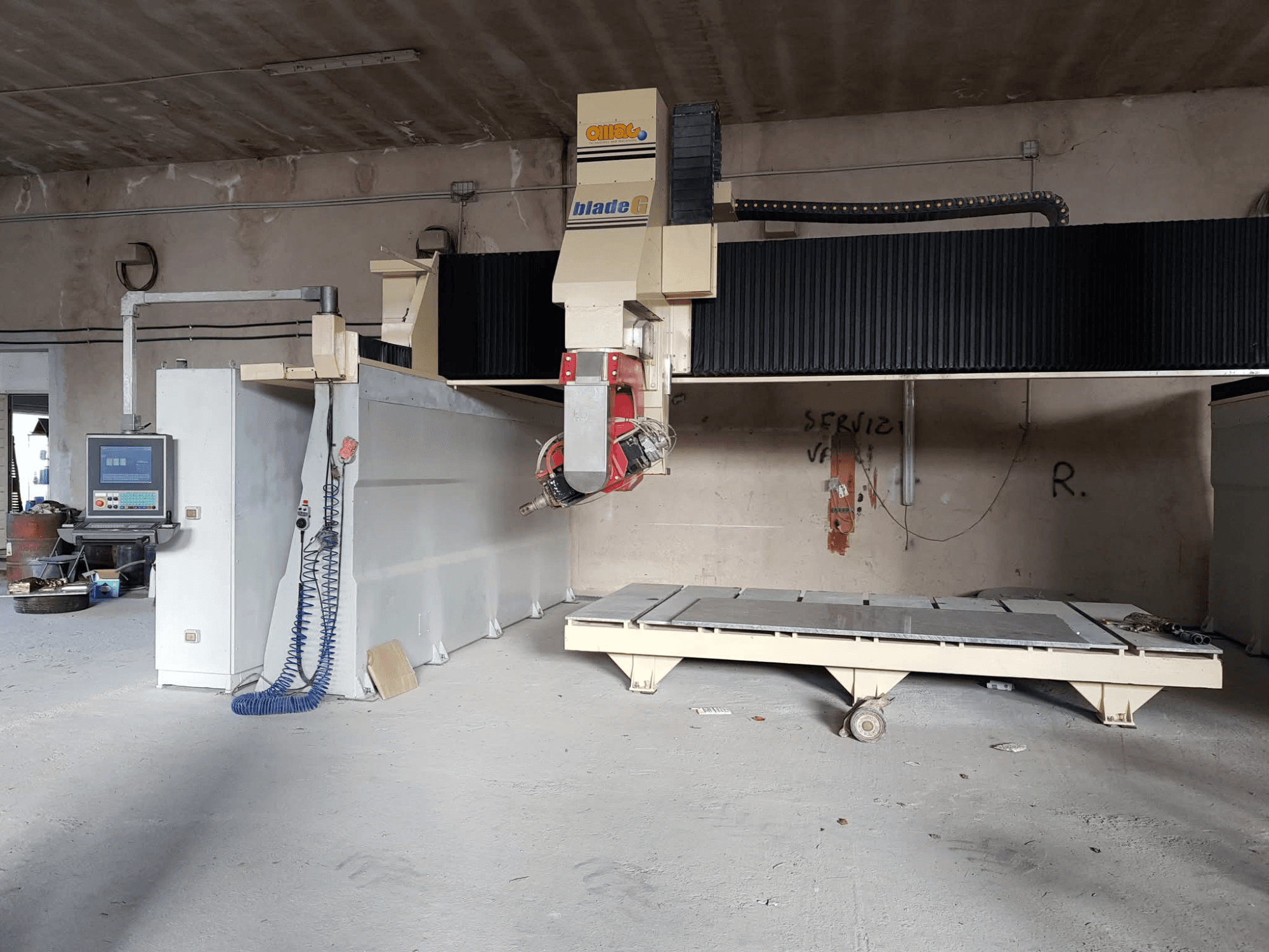Gantry-jyrsin OMAG Blade G työpajassa, etukuva, jossa ohjauspaneeli ja suuri jyrsintätaso näkyvissä.