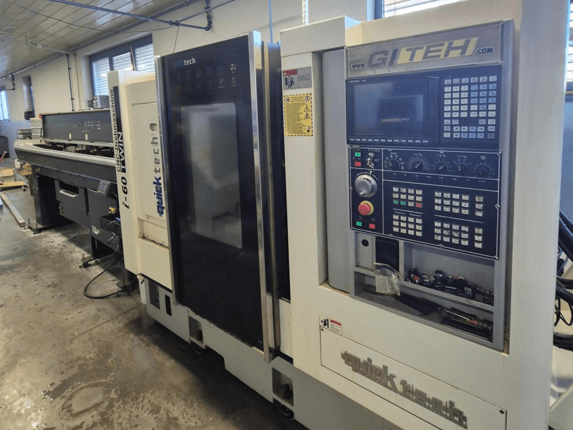 Quick Tech i-60 twin CNC-kone, etukuva, jossa on GITEH-ohjauspaneeli ja käyttöpainikkeet, työpajassa.