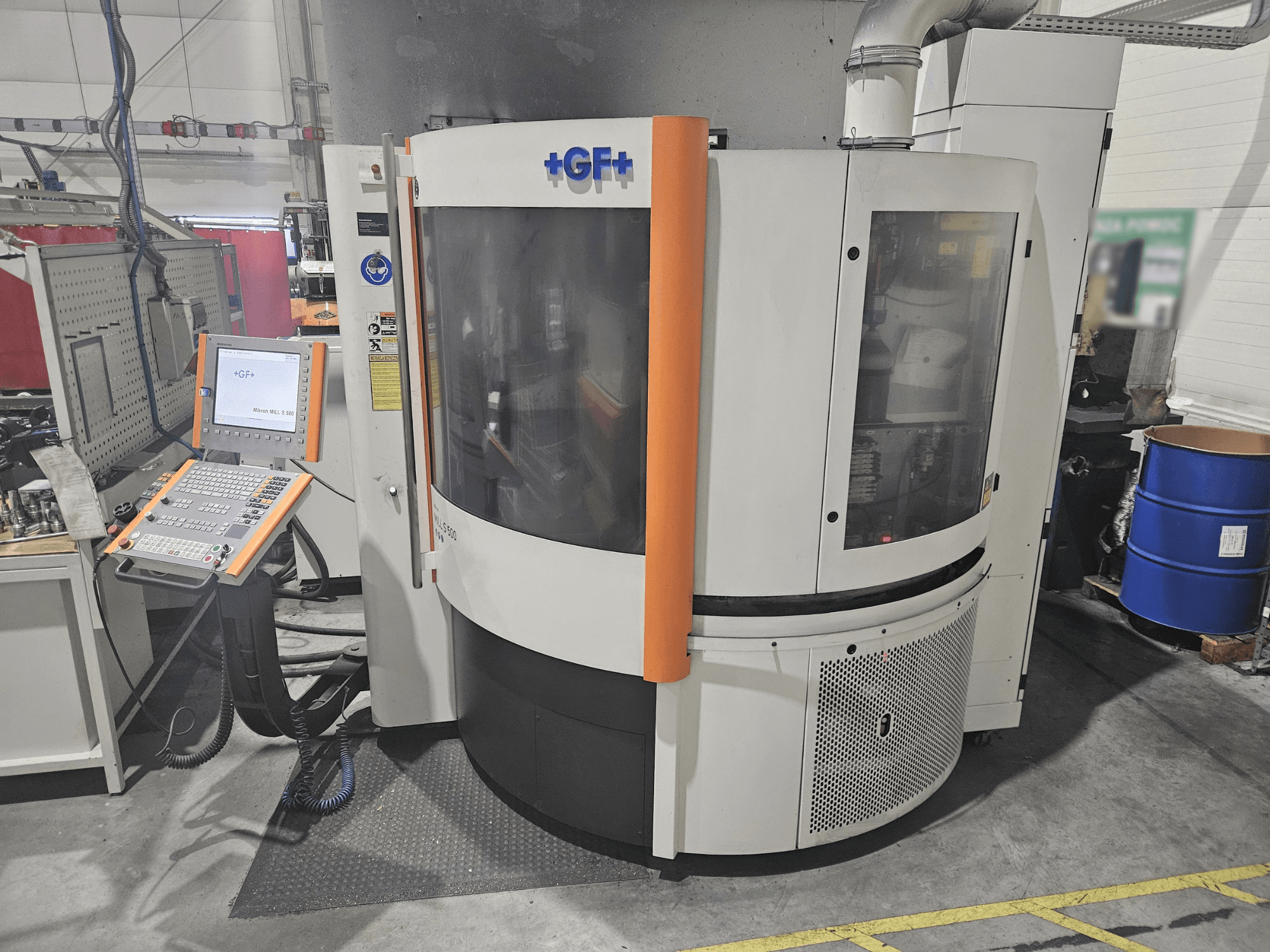 GF Machining Solutionsin työstökone, jossa on ohjauspaneeli, etukuva; läpinäkyvä paneeli, oranssit korostukset ja teollisuusasetus.