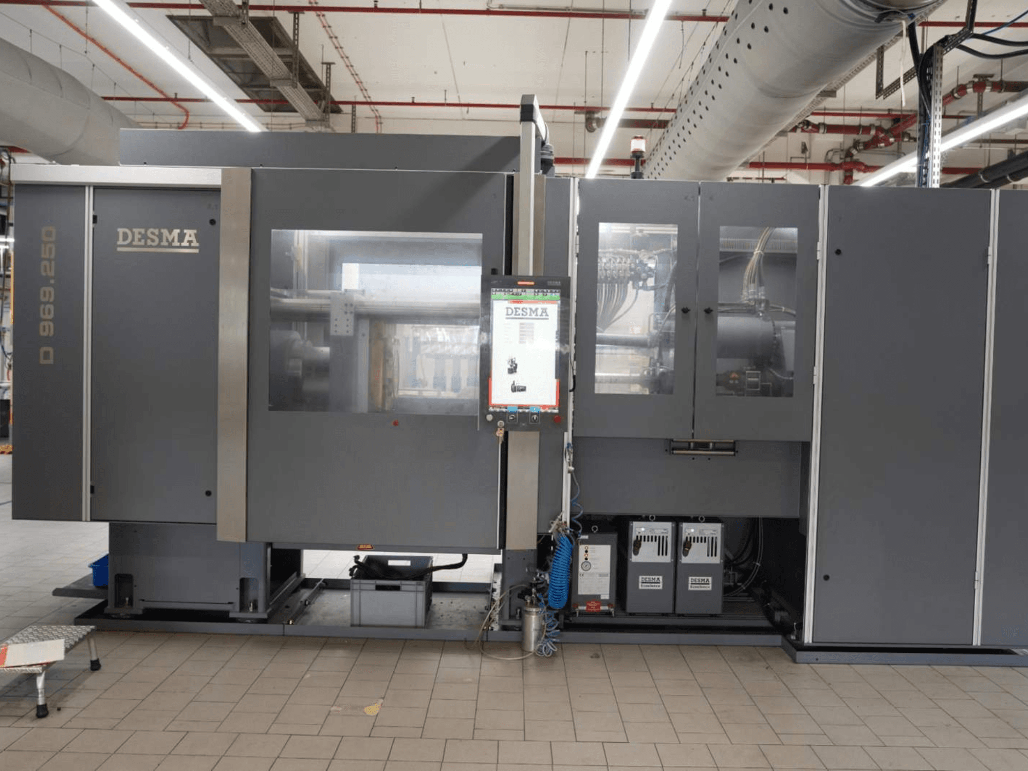 Kloeckner Desma D 969.250 Z (S3) -pystysuora ruiskuvalukone tehdasympäristössä, etunäkymä ohjauspaneelin kanssa.