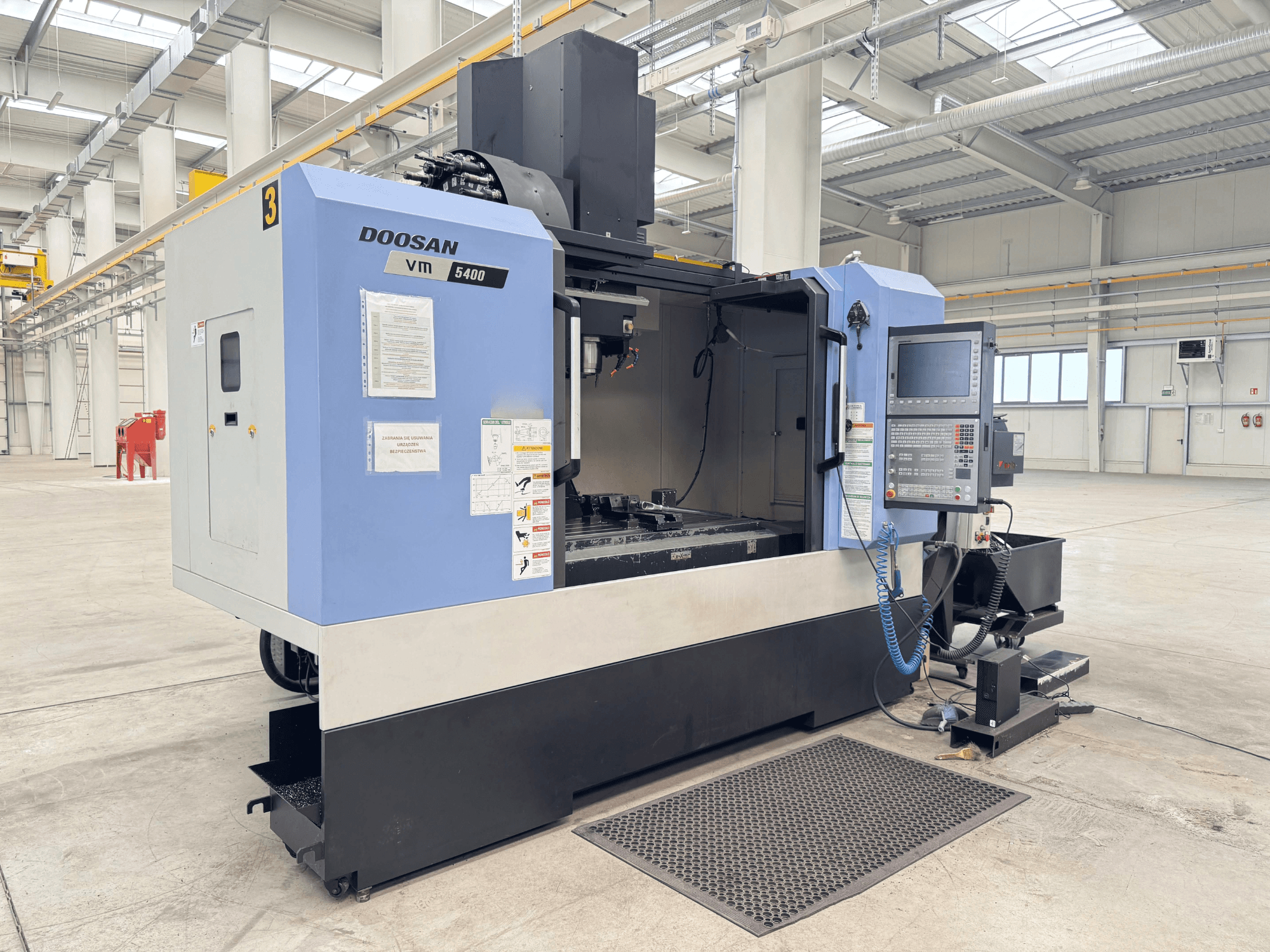 DOOSAN VM 5400 -pystytyöstökeskus, etukuva, jossa näkyy ohjauspaneeli ja työalue tilavassa teollisuusympäristössä.