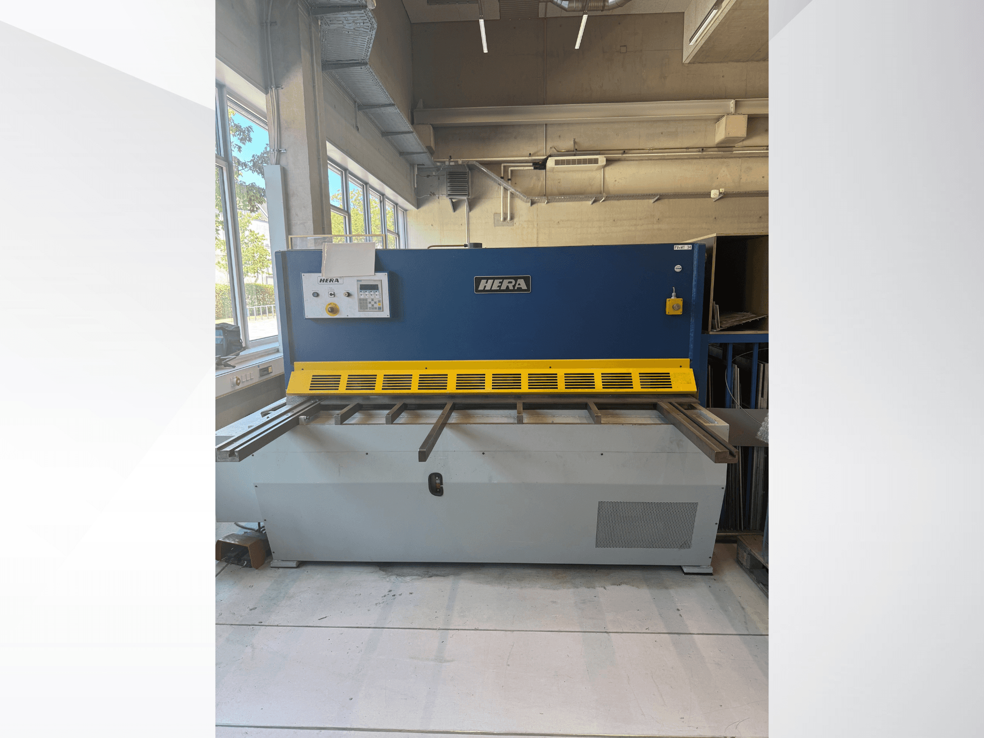 HERA TS 2000x6 -hydraulinen leikkauskone edestä katsottuna; laitteessa on sininen ja keltainen väritys sekä ohjauspaneeli ja leikkuualusta.