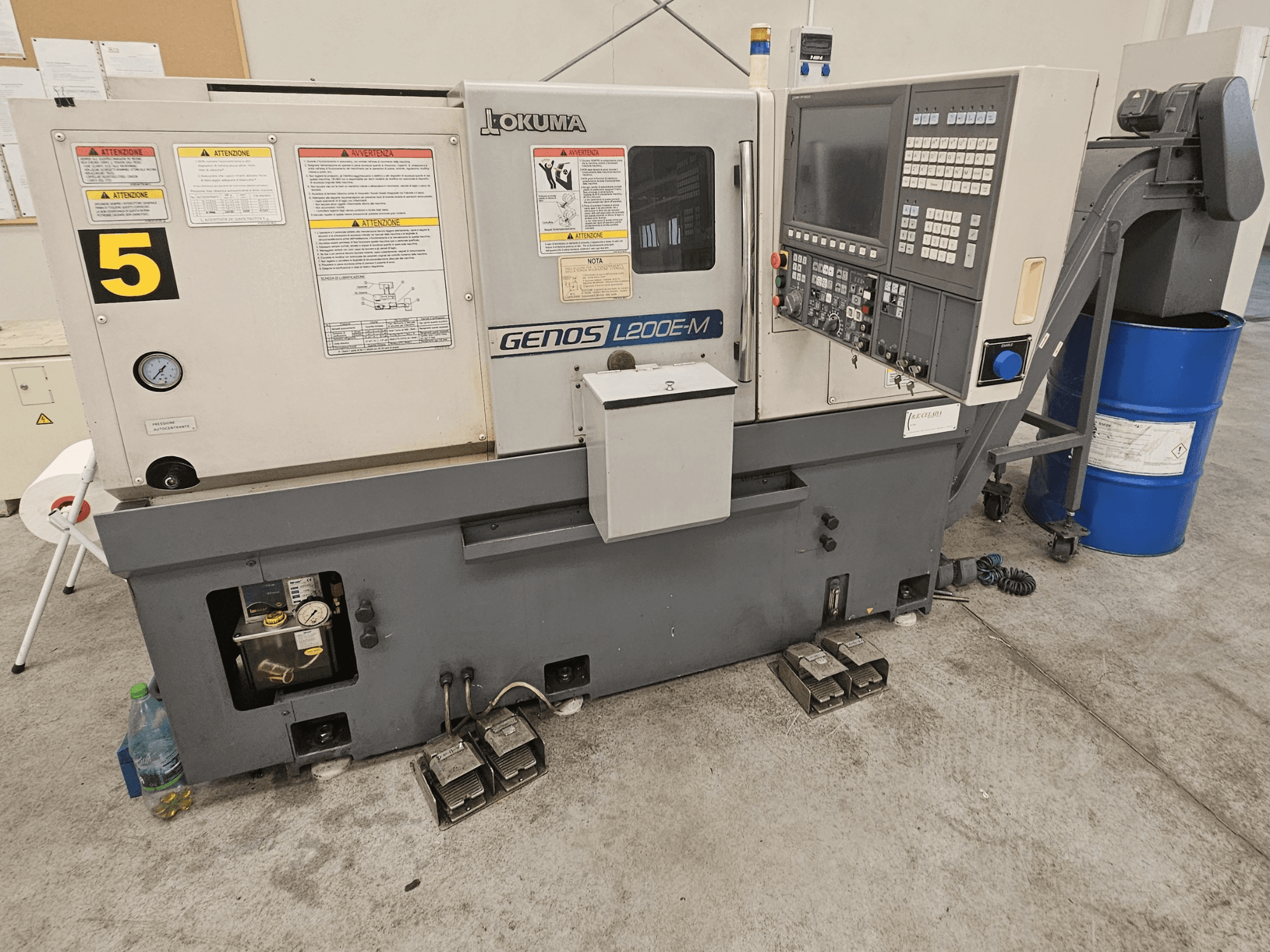 Okuma GENOS L200E-M vaakasuora sorvauskone edestä, jossa on ohjauspaneeli, tarrat ja jäähdytysnestetynnyri.