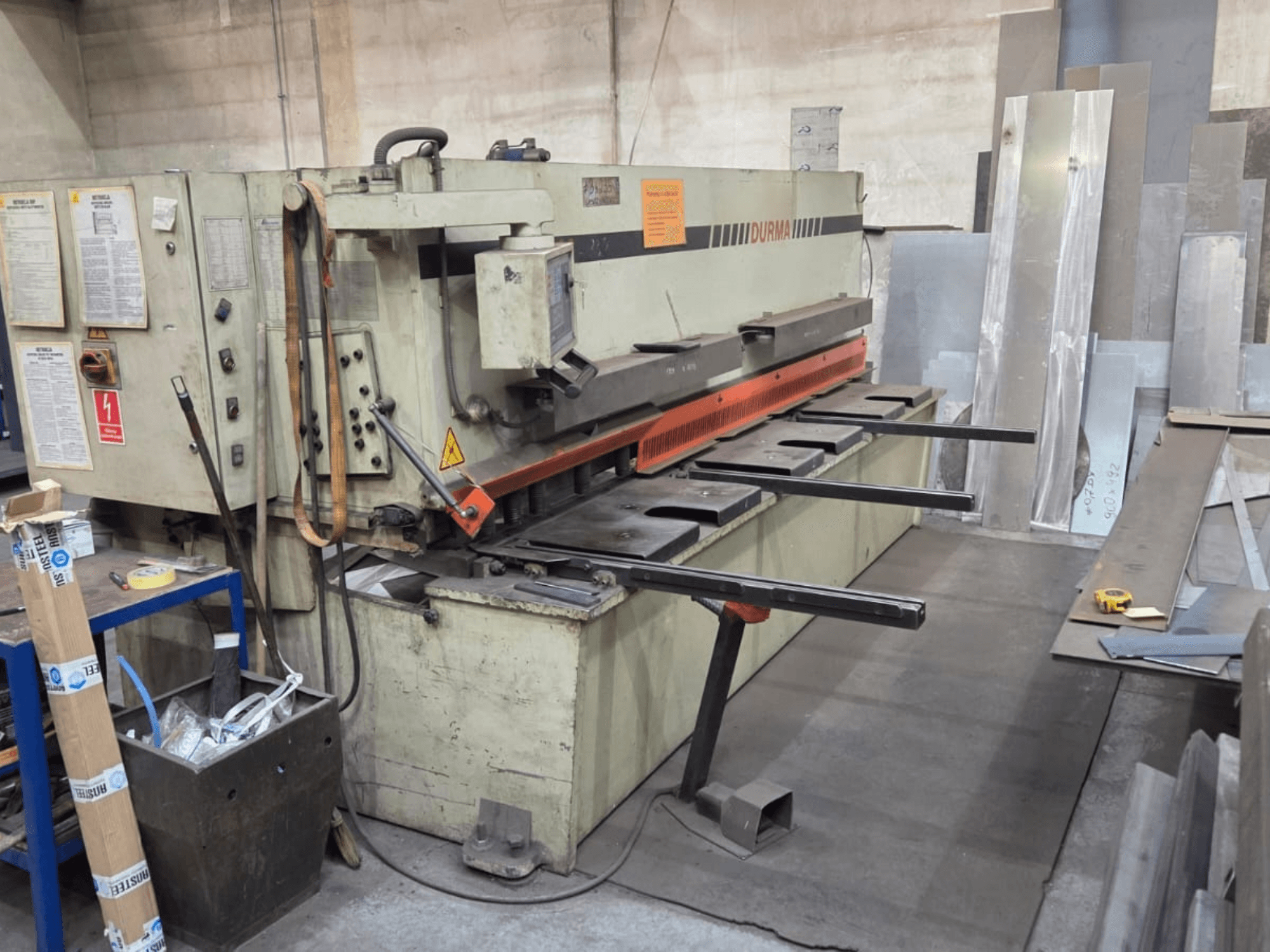 Hydraulinen leikkauskone Durma SB 3060, etukuva, jossa näkyy hallintalaitteet, leikkuuterä ja metallilevyt työtilassa.