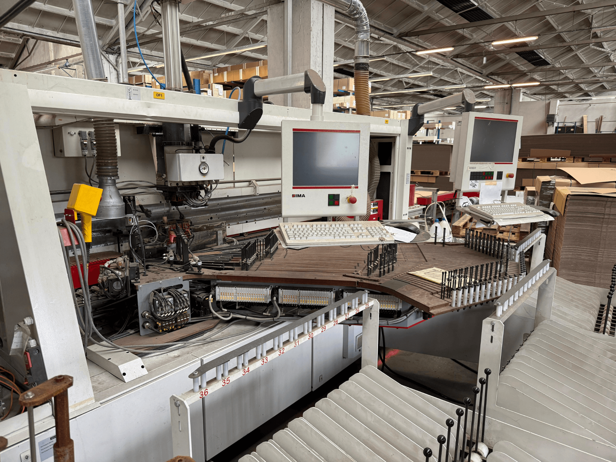 IMA-tarkkuuspuuntyöstökone, jossa on kaksi näyttöä ja ohjauspaneelit, etukuva, jossa näkyy kuljetin ja työkalualue.