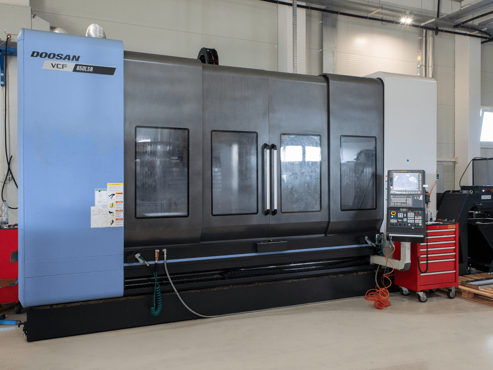 DOOSAN VCF850 -jyrsintä- ja sorvauskeskus, etunäkymä; varustettu suurilla kaksoisikkunoilla, ohjauspaneelilla ja työkalujen säilytystilalla. Ihanteellinen koneistukseen.