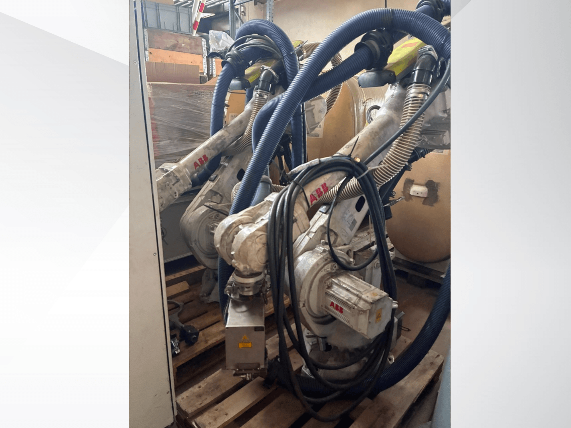 ABB IRB 4600-40/2.55 -robottivarsi, sivukuva, jossa näkyvät kaksi vartta ja niihin kiinnitetyt letkut; asennettuna kuormalavoille varastotilassa.