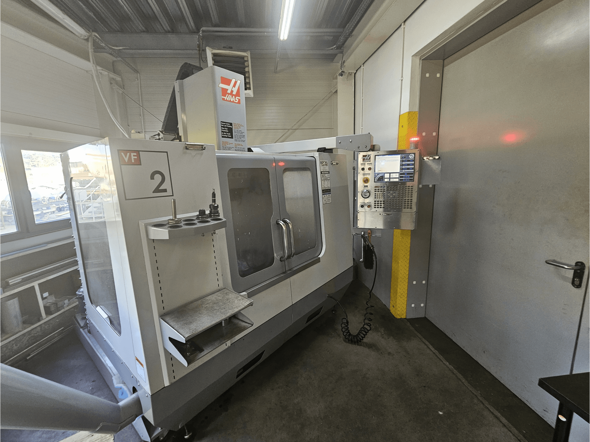Haas VF-2 CNC-jyrsinkone, etukuva, jossa näkyy ohjauspaneeli, työkalunpitimet ja selkeä ikkuna työalueelle.