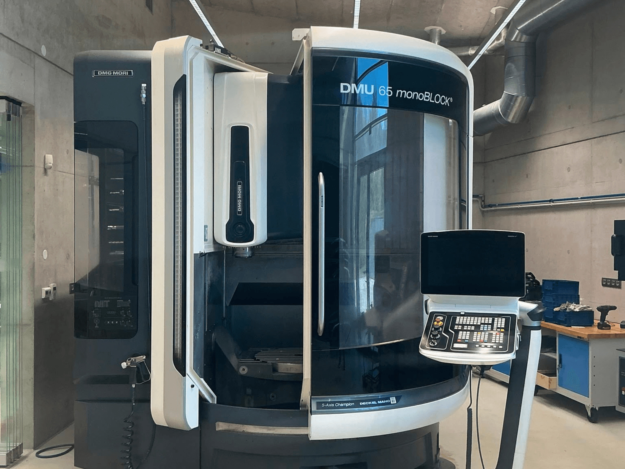 DMG MORI DMU 65 monoBLOCK -pystykoneistuskeskus, etunäkymä, jossa näkyvät ohjauspaneeli ja koneen yksityiskohdat työpajaympäristössä.